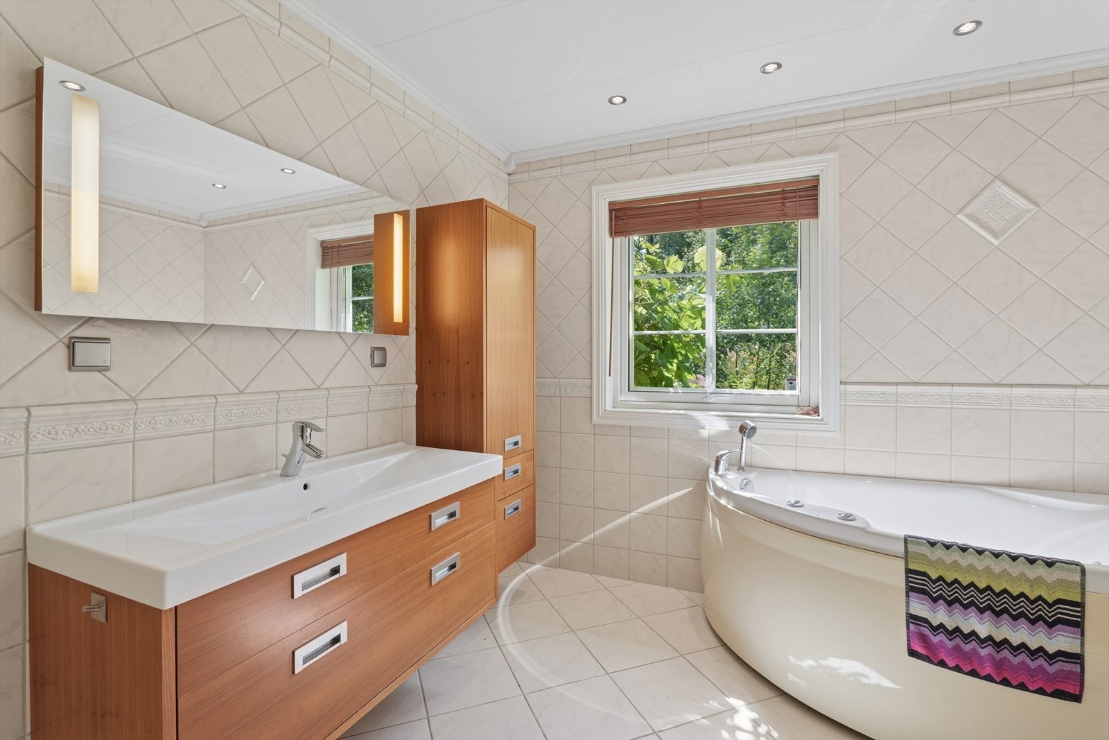 Badet er romslig og moderne fra byggeår, med lyse fliser på både gulv og vegger som gir et rent og tidløst uttrykk. Galleribilde