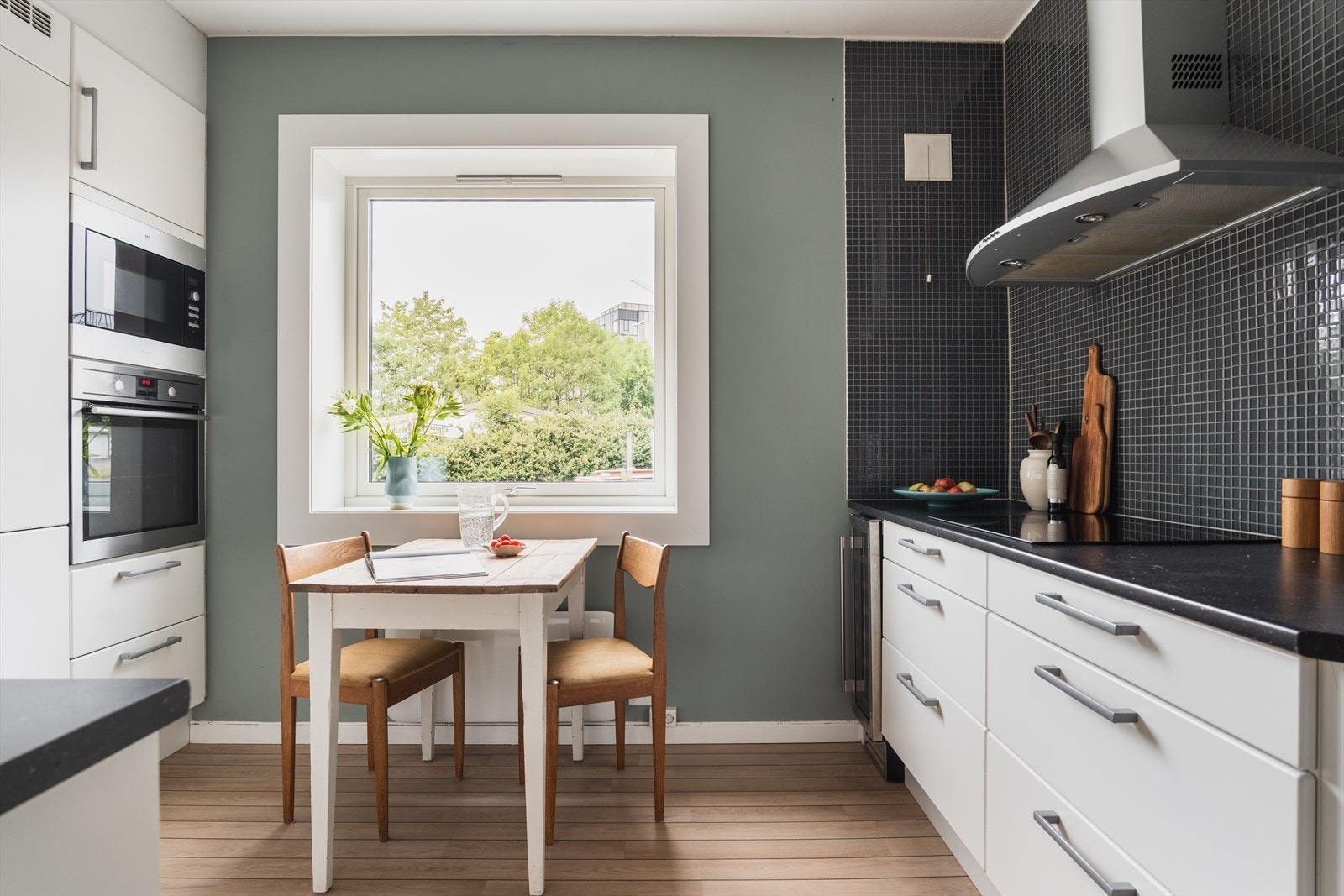 Kjøkkeninnredningen har glatte fronter, belysning under overskap og mosaikkfliser på vegg over benkeskap Galleribilde