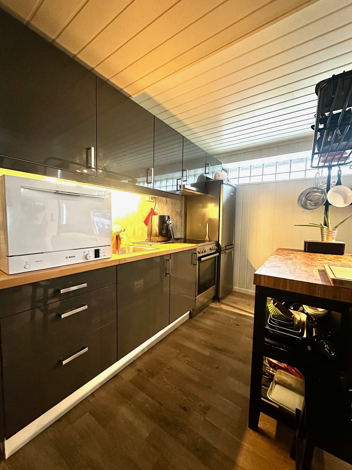 Fint kjøkken med frittstående hvitevarer som komfyr, kombiskap og vaskemaskin (på benken). Galleribilde