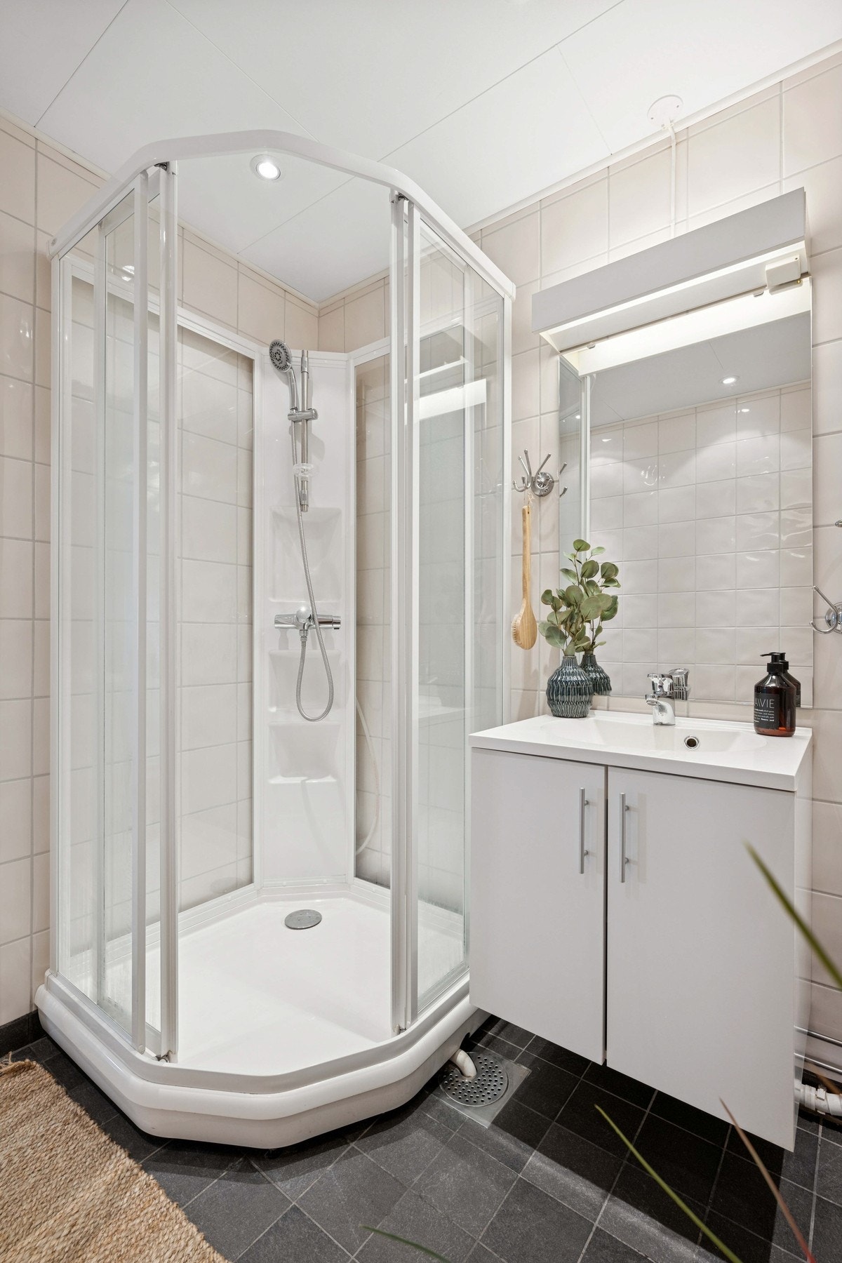 Baderommet er utstyrt med dusjkabinett, klosett, servantinnredning og speil på vegg. Galleribilde