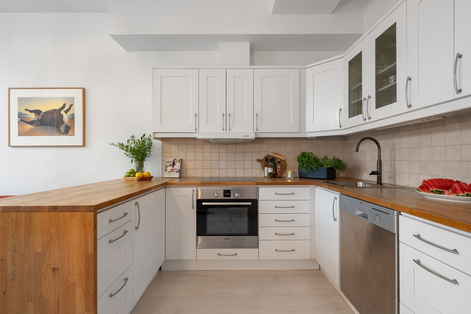 Pent kjøkken med heltre benkeplate. Hvitevarer (kjøleskap, oppvaskmaskin, komfyr) medfølger Galleribilde