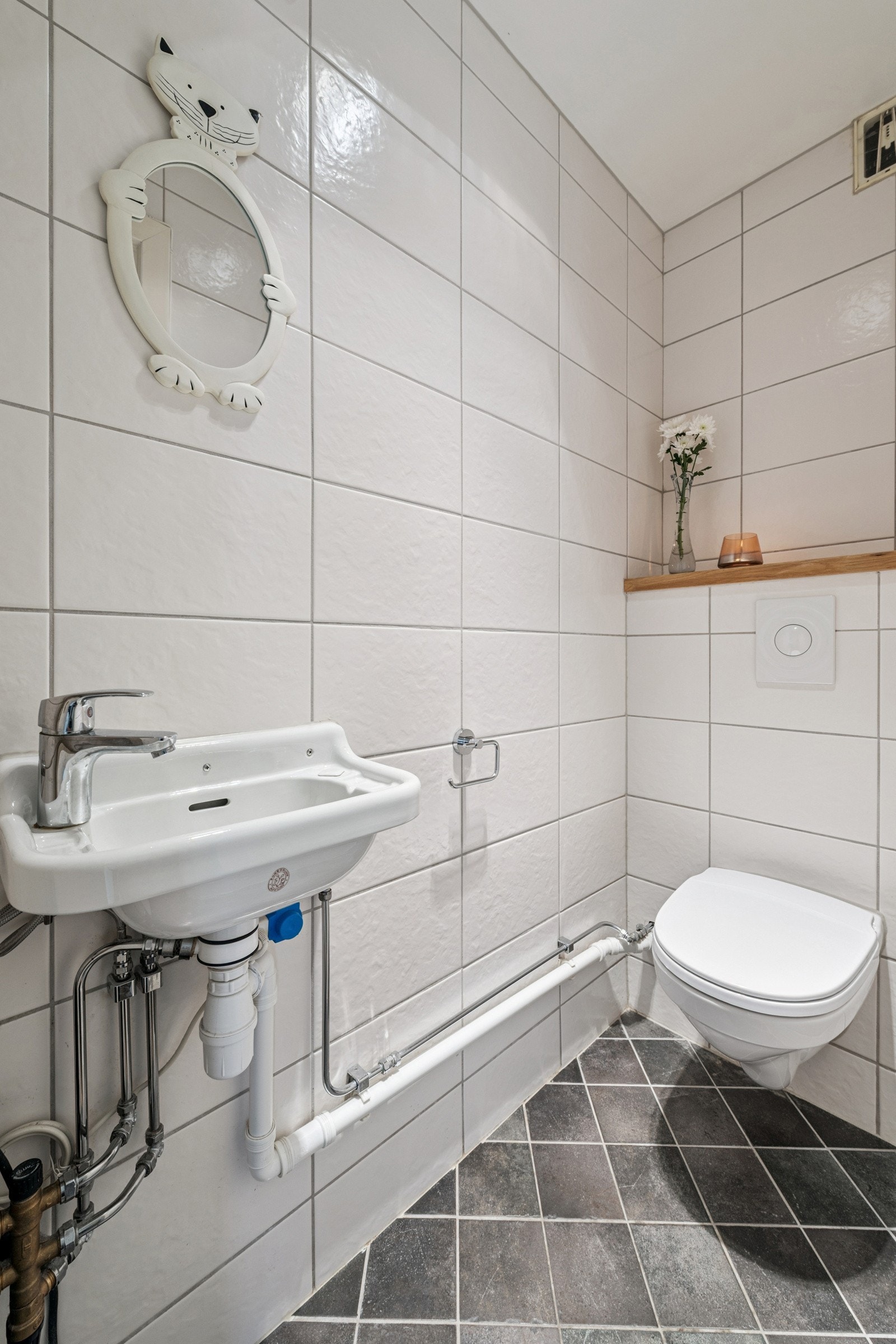 Praktisk, flislagt toalettrom med varmekabler i gulv, servant og veggmontert klosett. Høiax varmtvannsbereder for varmtvann på servant på wc. Galleribilde