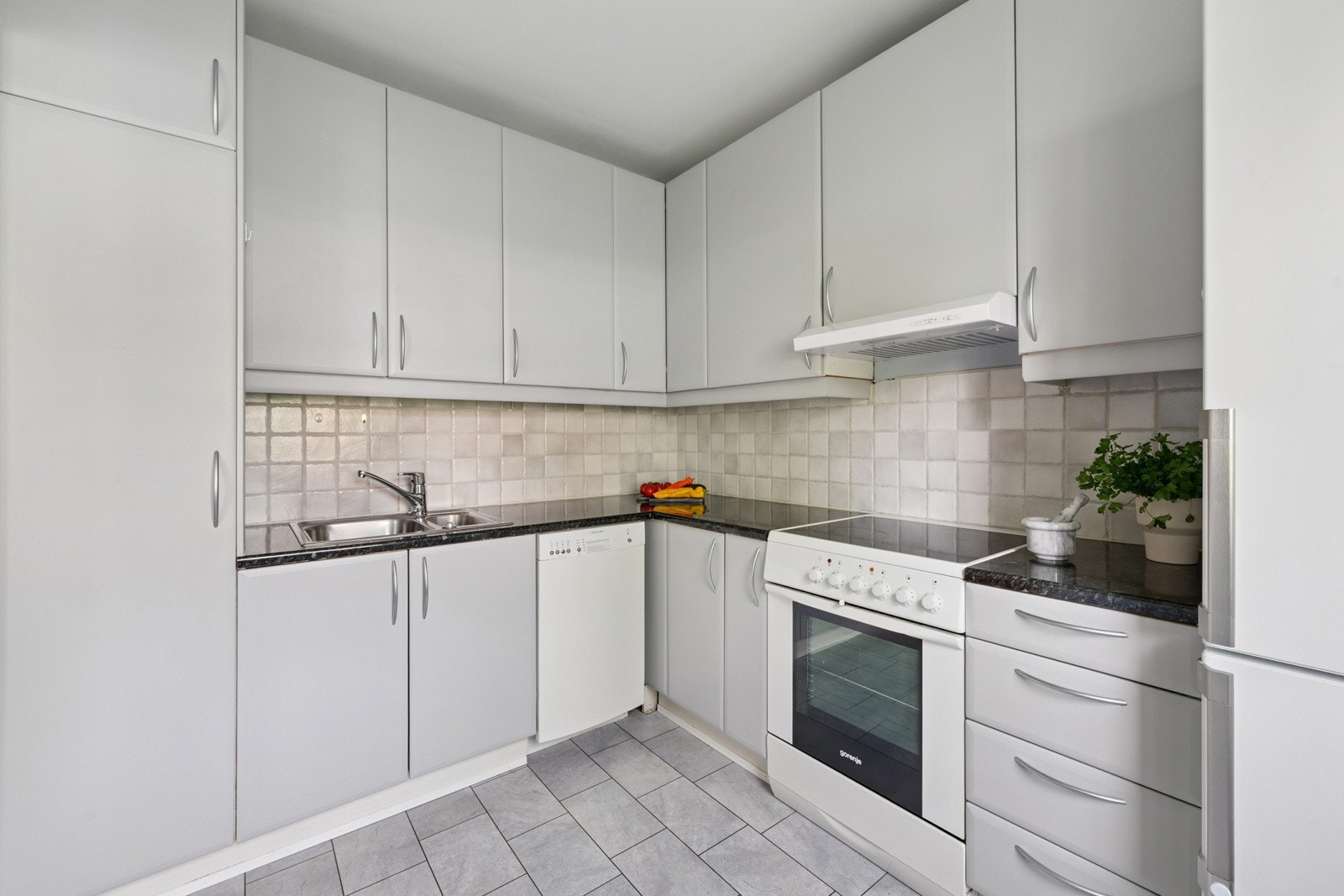 Lys kjøkkeninnredning med slette fronter og benkeplate i laminat. Fliser over benk. Ventilator og opplegg for oppvaskmaskin. Alle hvitevarer på kjøkken medfølger. Galleribilde