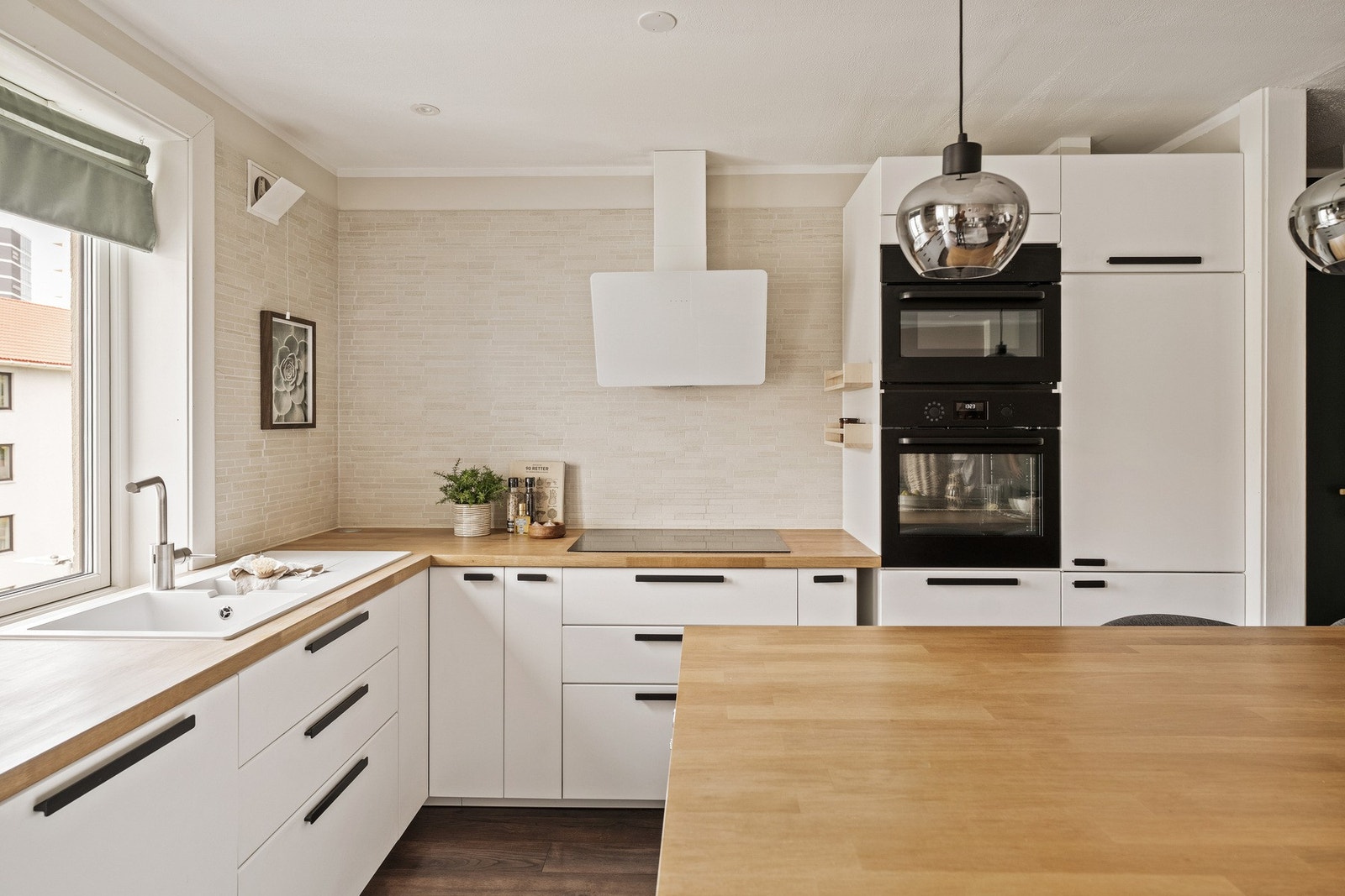 L-formet kjøkken med gjennomført uttrykk og integrerte hvitevarer. Galleribilde