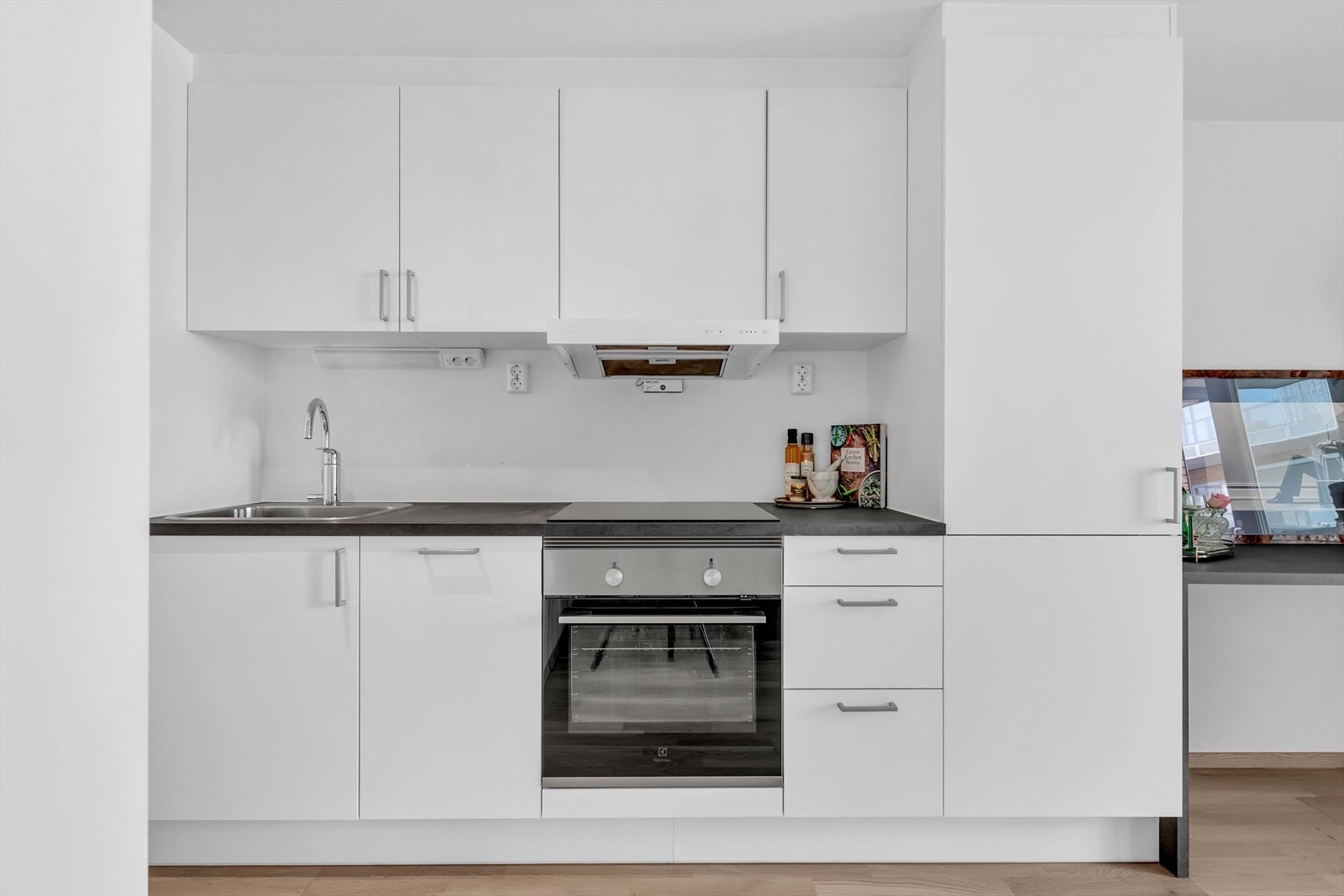 Kjøkkenet har en praktisk og stilren innredning med lyse, glatte fronter, laminert benkeplate og nedfelt oppvaskmaskin. Galleribilde