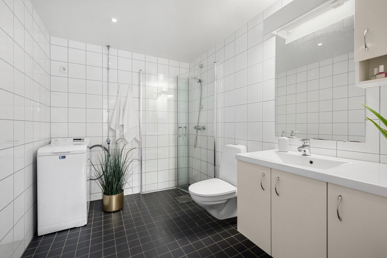 Bad av god størrelse med flislagt gulv og vegger, varmekabler og downlights. Det er opplegg for vaskemaskin. Galleribilde