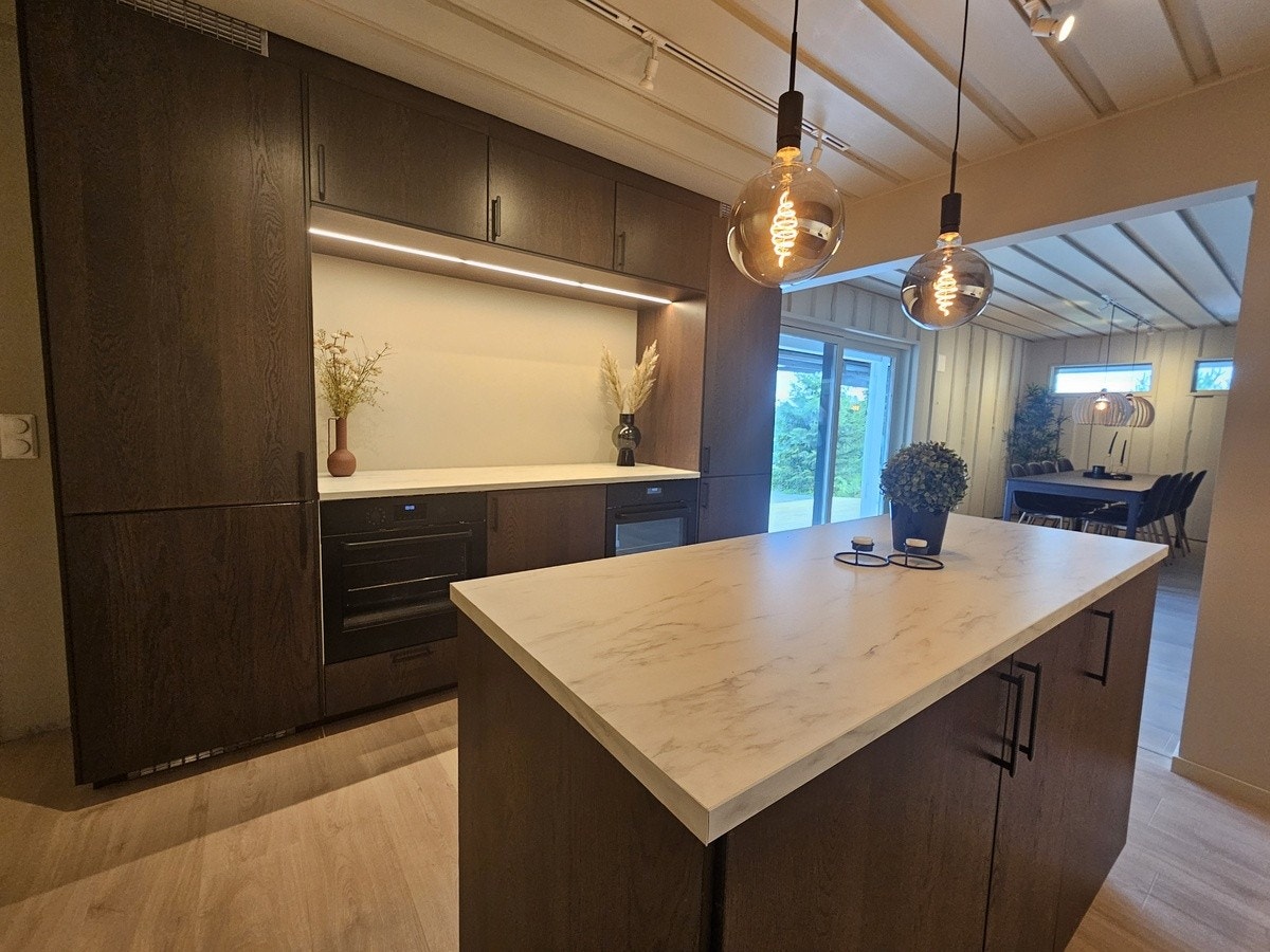 På andre siden av kjøkkenet er det to integrerte stekovner, to integrerte kjøleskap/frys og ekstra benkeplass i mellom. Galleribilde