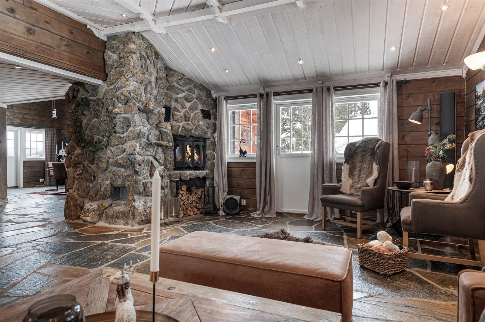 Også i stuen har du en viderføring av den rustikke peisinnsatsen kledd i naturstein og skiferbelagt gulv. Stuen har god takhøyde og det er downlights med dimmer i tak, samt varme i gulvet. Galleribilde