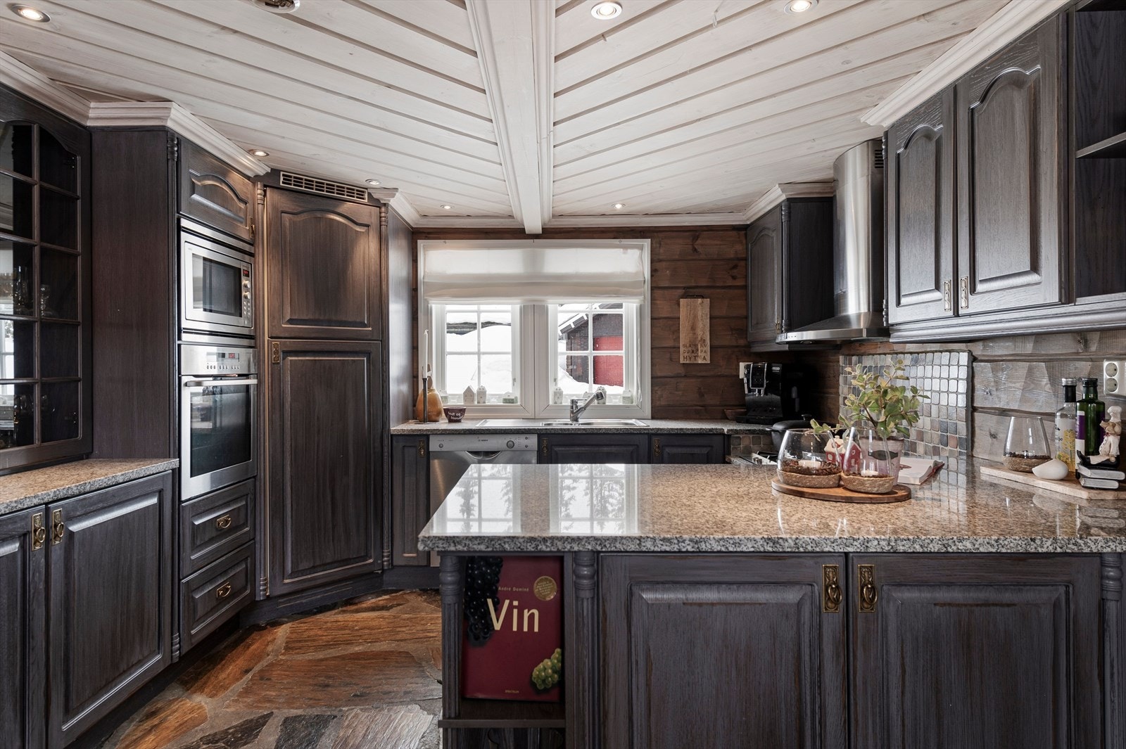 Innredningen har profilerte fronter og en eksklusive benkeplate i stein. Merk også et stort kjølehjørne, samt integrerte hvitevarer som bidrar til et ryddig og pent preg. Hvitevarene medfølger i salget Galleribilde