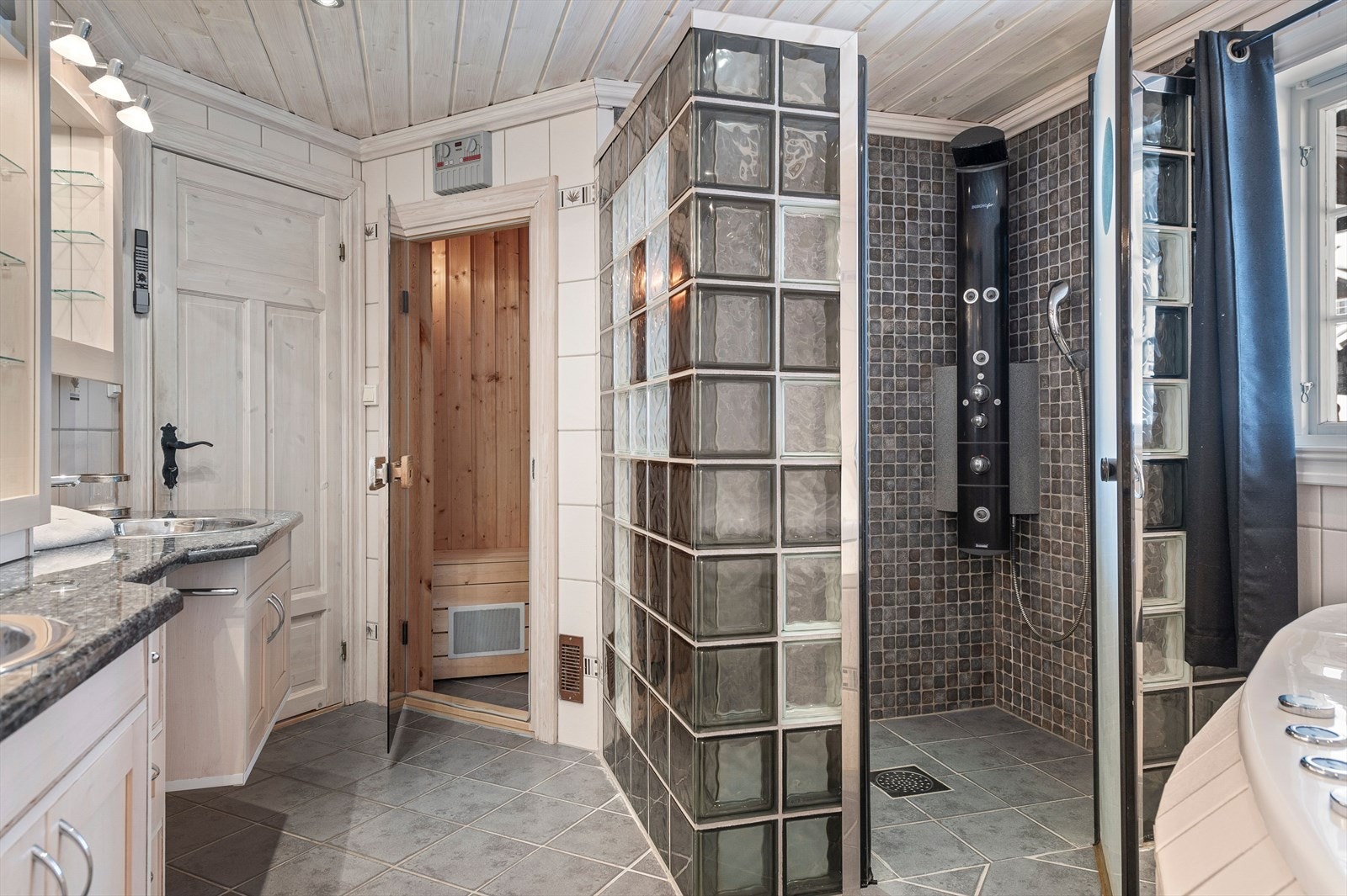 Det romslige badet har en stor dusjnisje med glasbyggerstein og dør. I tillegg er det hjørneboblebad i rommet, vegghengt wc og en herlig badstue. Galleribilde