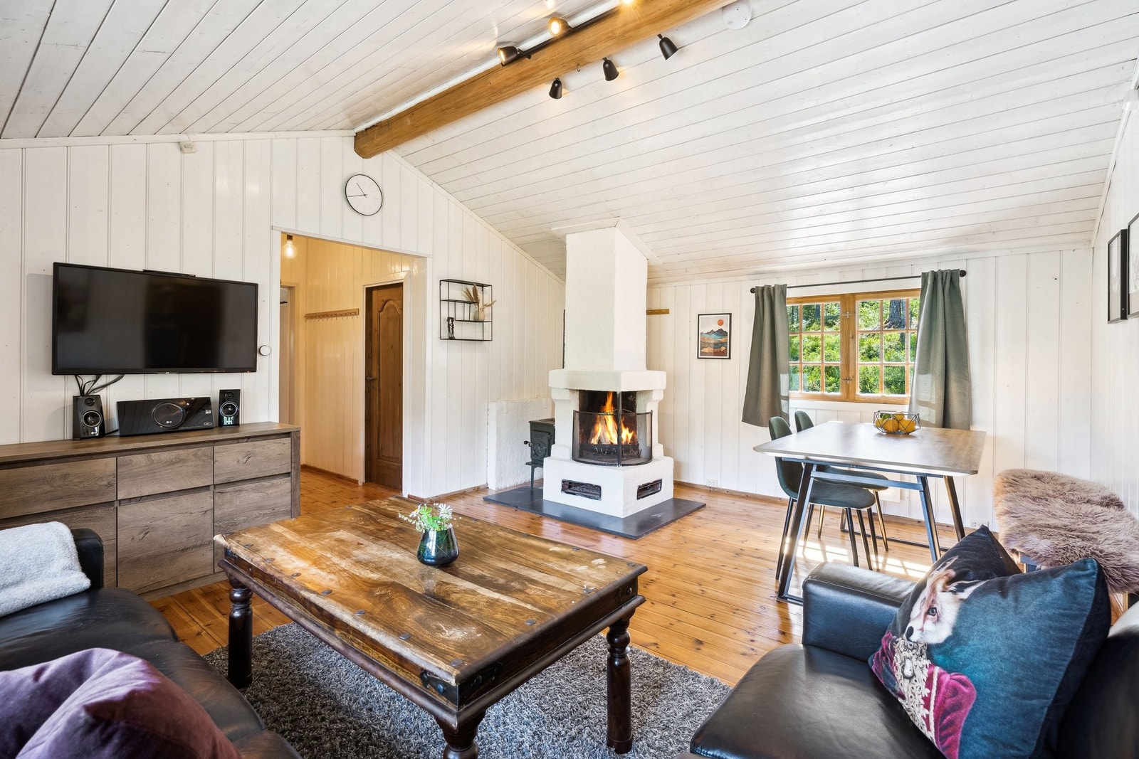 Stua er luftig og malt i lyse farger. Den er delt i to soner med gjennomgående lys. I bakre hjørnet ser vi den store peisen. Bak peisen står en Jøtul ovn som varmer raskt opp hytta vinterstid. Galleribilde