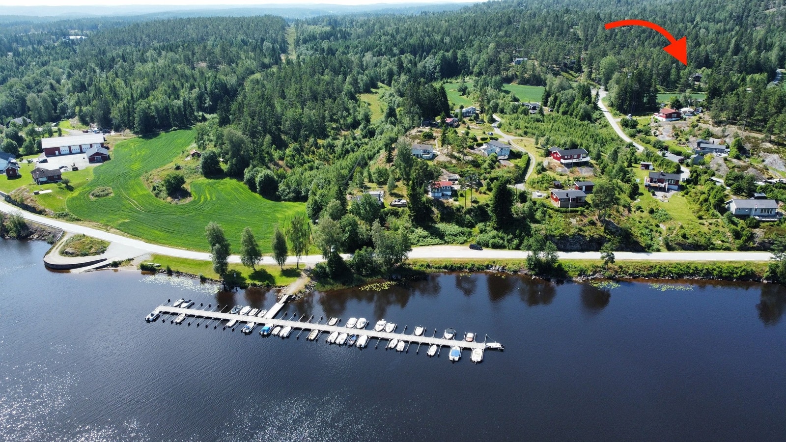 Skotsbergåsen fra nordøst. Bildet viser nedre del av hyttefeltet, med hytta (markert med pil) i øvre, høyre hjørnet. Fra hytta er det kun fem minutter ned til båthavna. Til venstre i bildet ser vi stranda og rasteplassen som tilhører feltet. Galleribilde