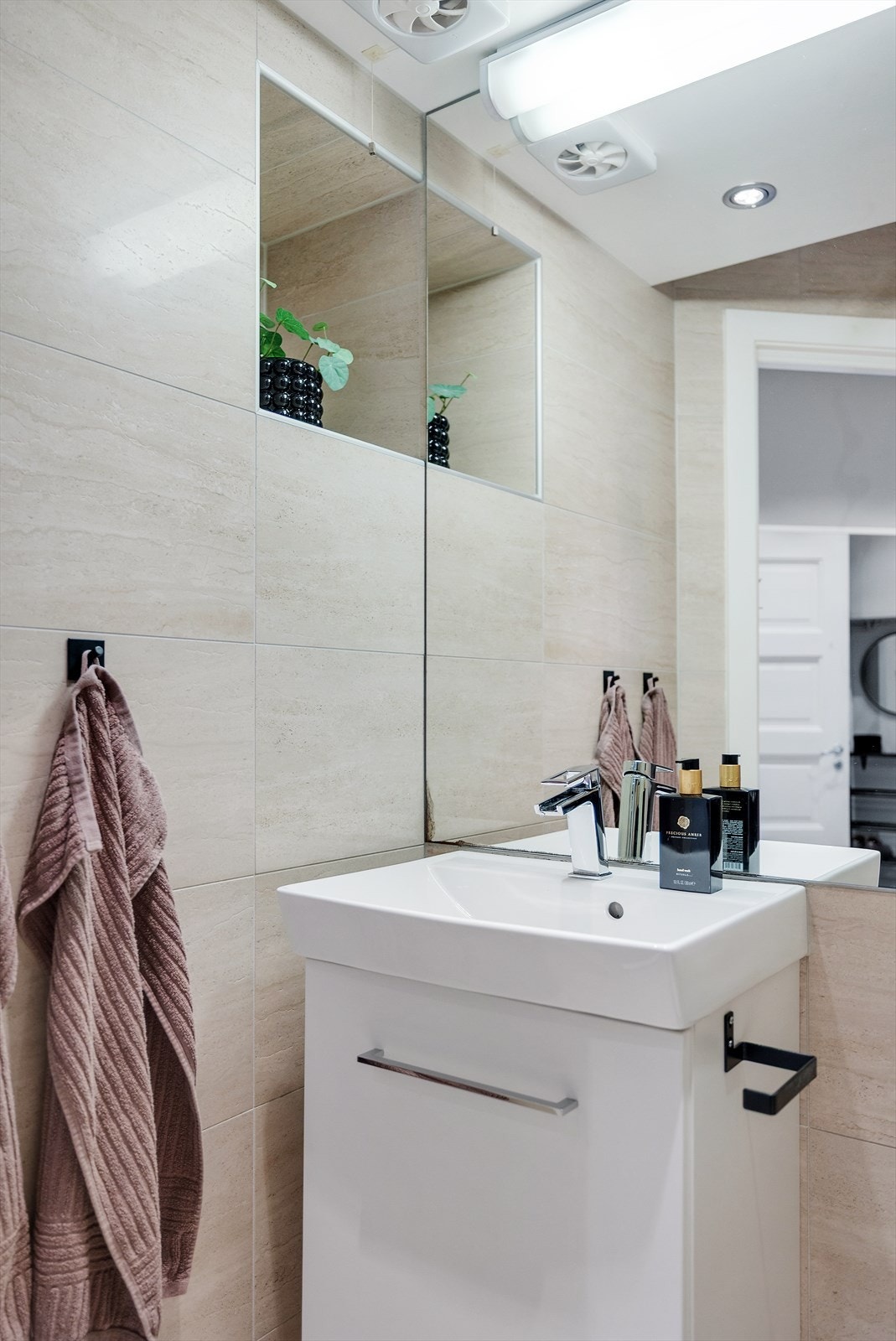 Lys baderomsinnredning med servant med oppbevaring, veggmontert speil, vegghengt toalett og dusjhjørne. Praktisk hylleløsning til venstre for servant som er perfekt til ekstra oppbevaring. Galleribilde