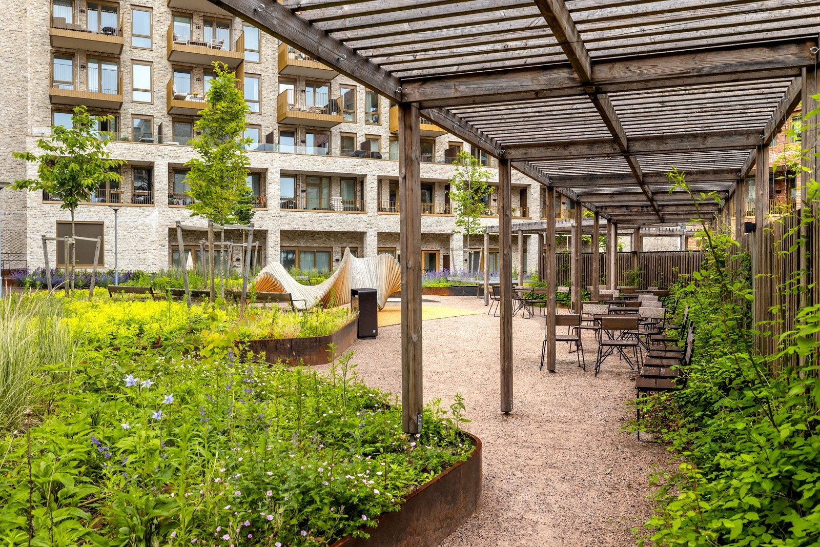 Gårdsrommet er pent opparbeidet med beplantning og sitteplasser som innbyr til hyggelig naboskap og gode pauser i hverdagen. Galleribilde