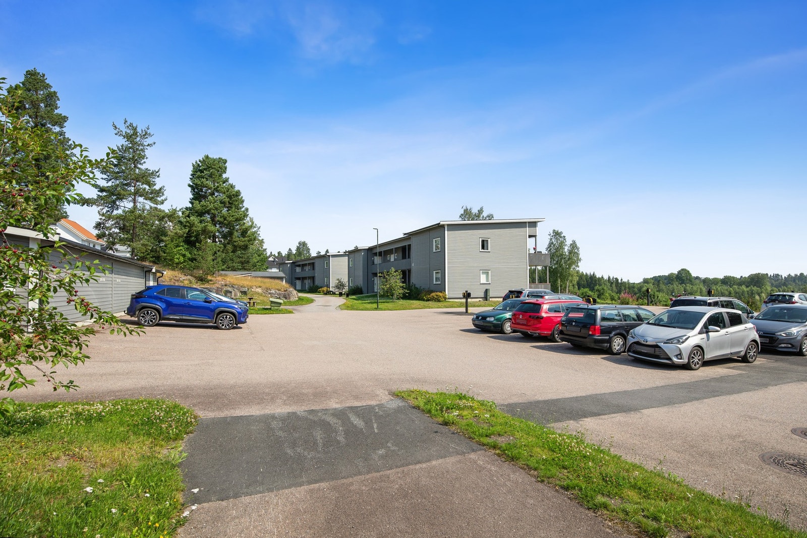 Like ved inngangspartiet finner du et romslig felles parkeringsområde med elbilladere, enkel adkomst og plass til både beboere og gjester. Galleribilde