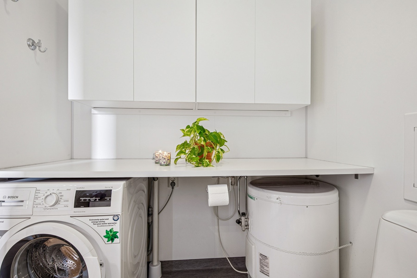 Her får du en funksjonell løsning med plass til både vaskemaskin og varmtvannsbereder. Overskap gir ekstra lagringsplass til det du ikke vil ha stående fremme. Galleribilde