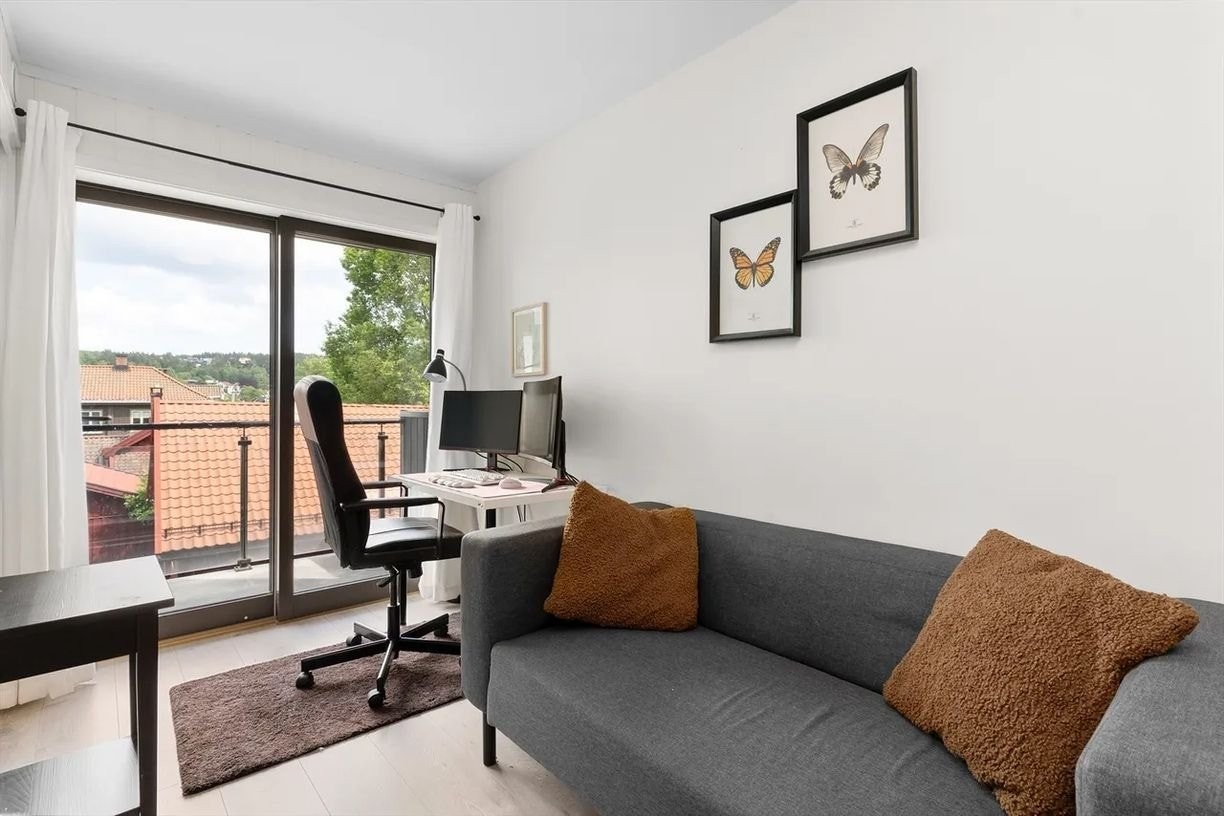 Stuen har en rolig og avslappende atmosfære med store vindusflater som slipper inn rikelig med dagslys. Her er det plass til både sofakrok og hjemmekontor – og direkte utgang til solrik balkong. Galleribilde