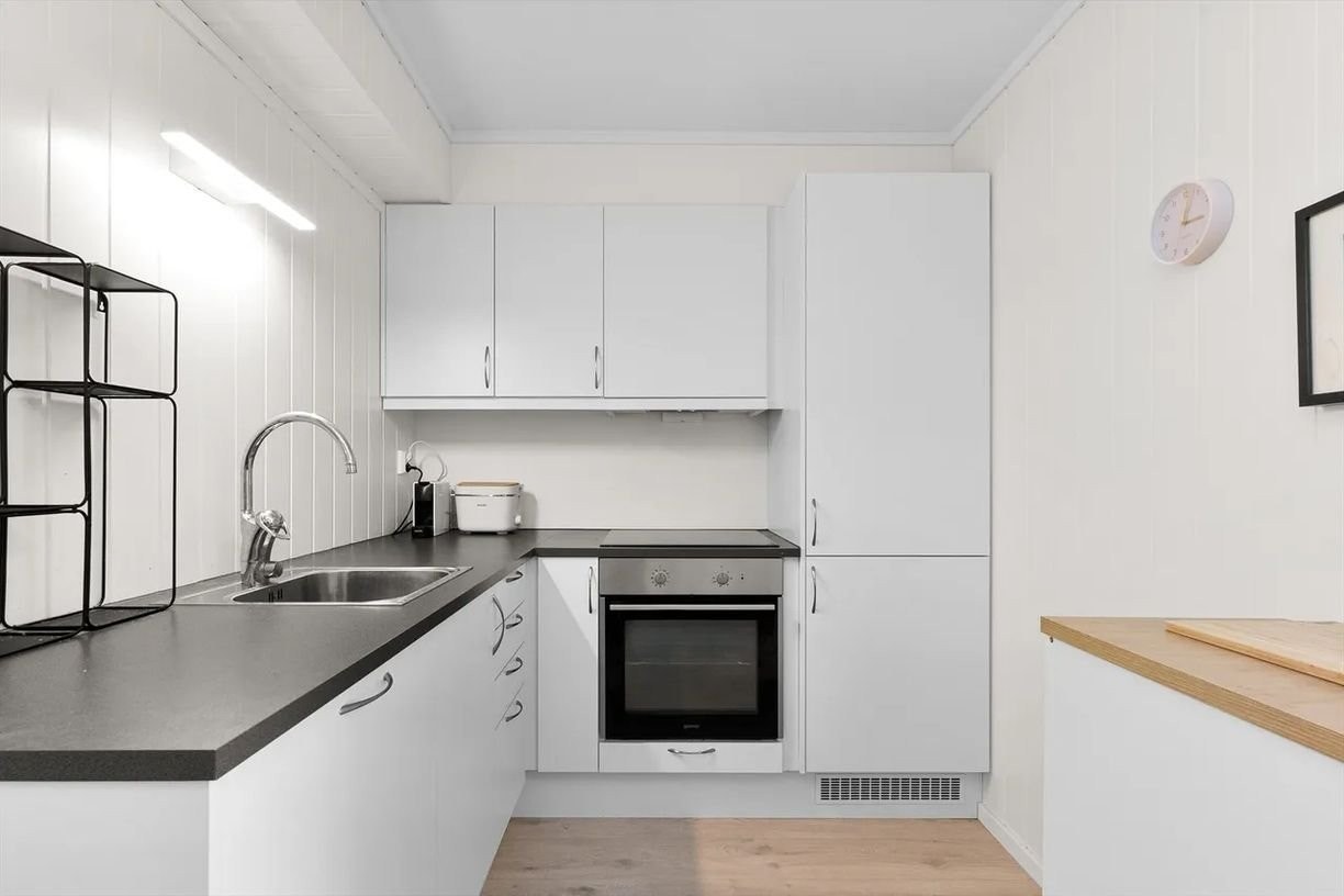 Lyst og moderne kjøkken i klassisk L-form, med smarte løsninger og alt du trenger lett tilgjengelig. Galleribilde