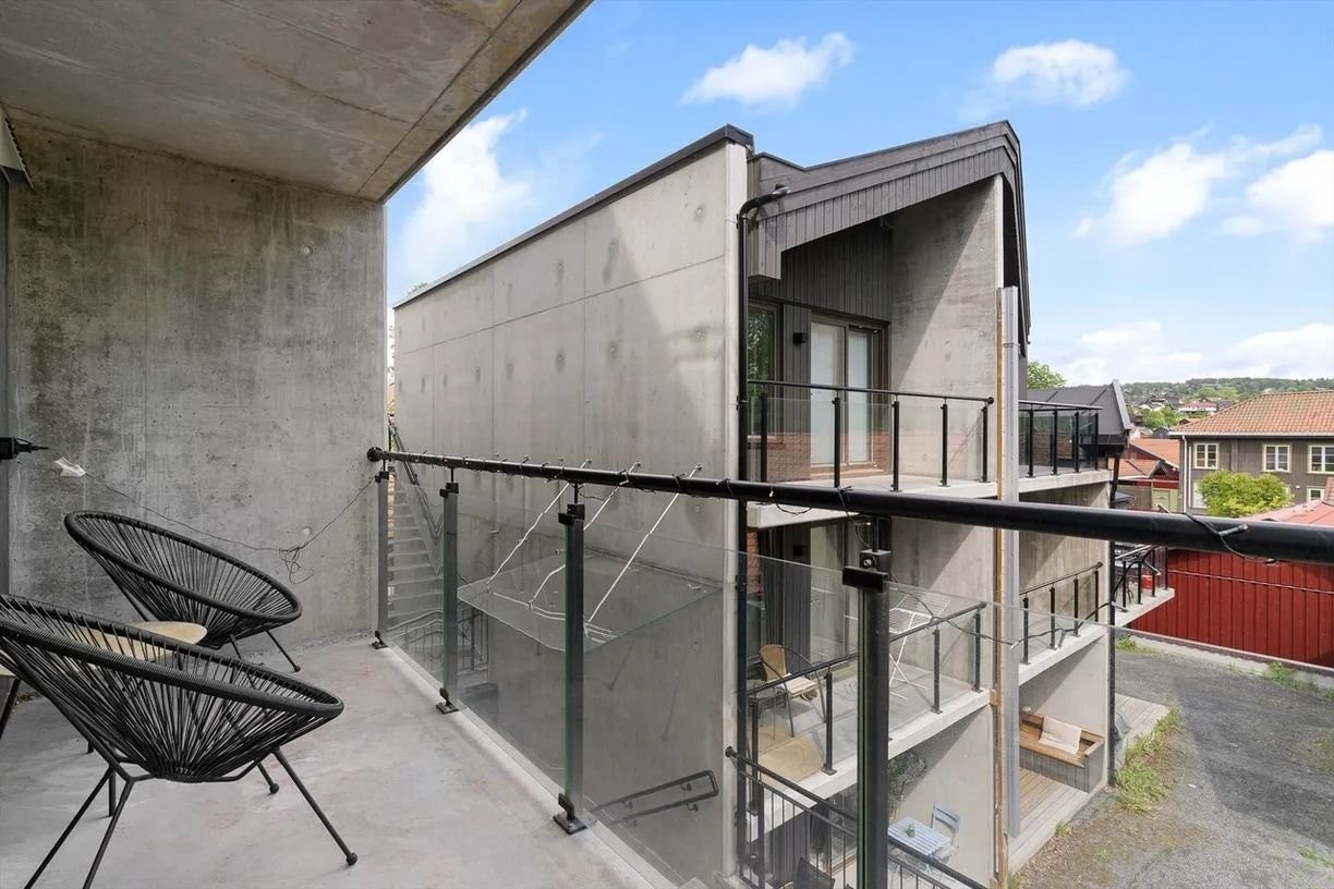 Romslig og overbygd balkong med glassrekkverk – en lun uteplass med god plass til utemøbler og mulighet for tørkestativ. Her kan du nyte morgenkaffen med utsikt over nabolaget og inn mot byen. Galleribilde