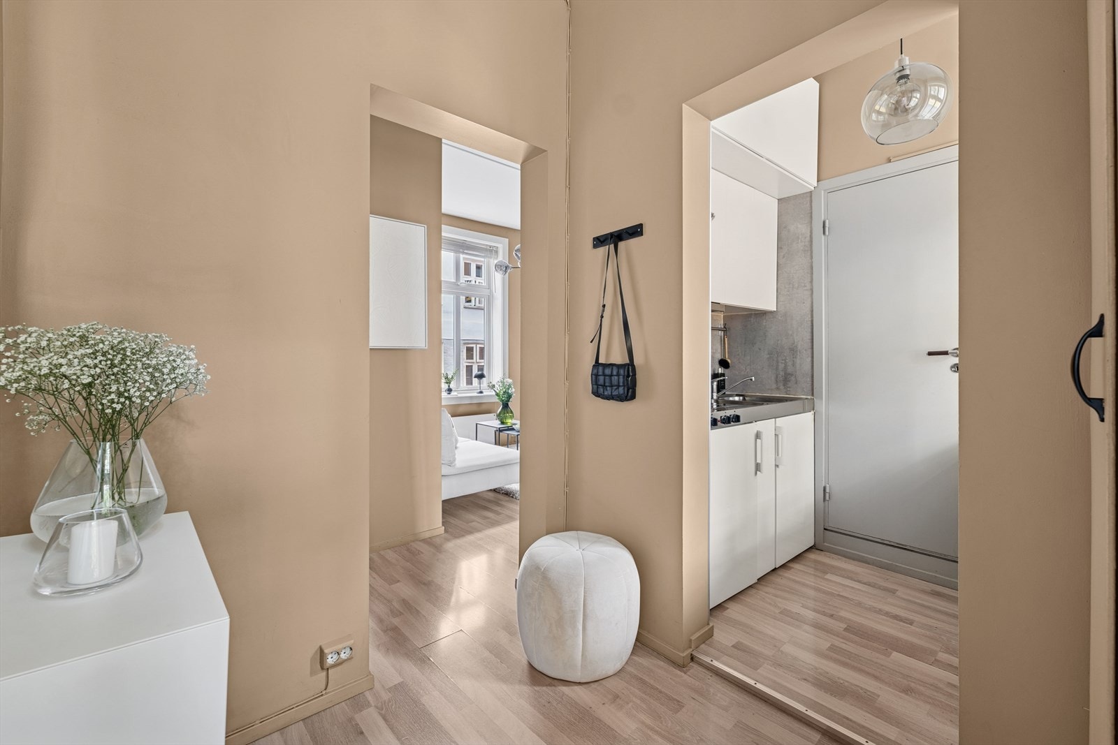 Entréen fungerer som et naturlig knutepunkt i leiligheten, med enkel tilgang til både stue og kjøkken. Galleribilde