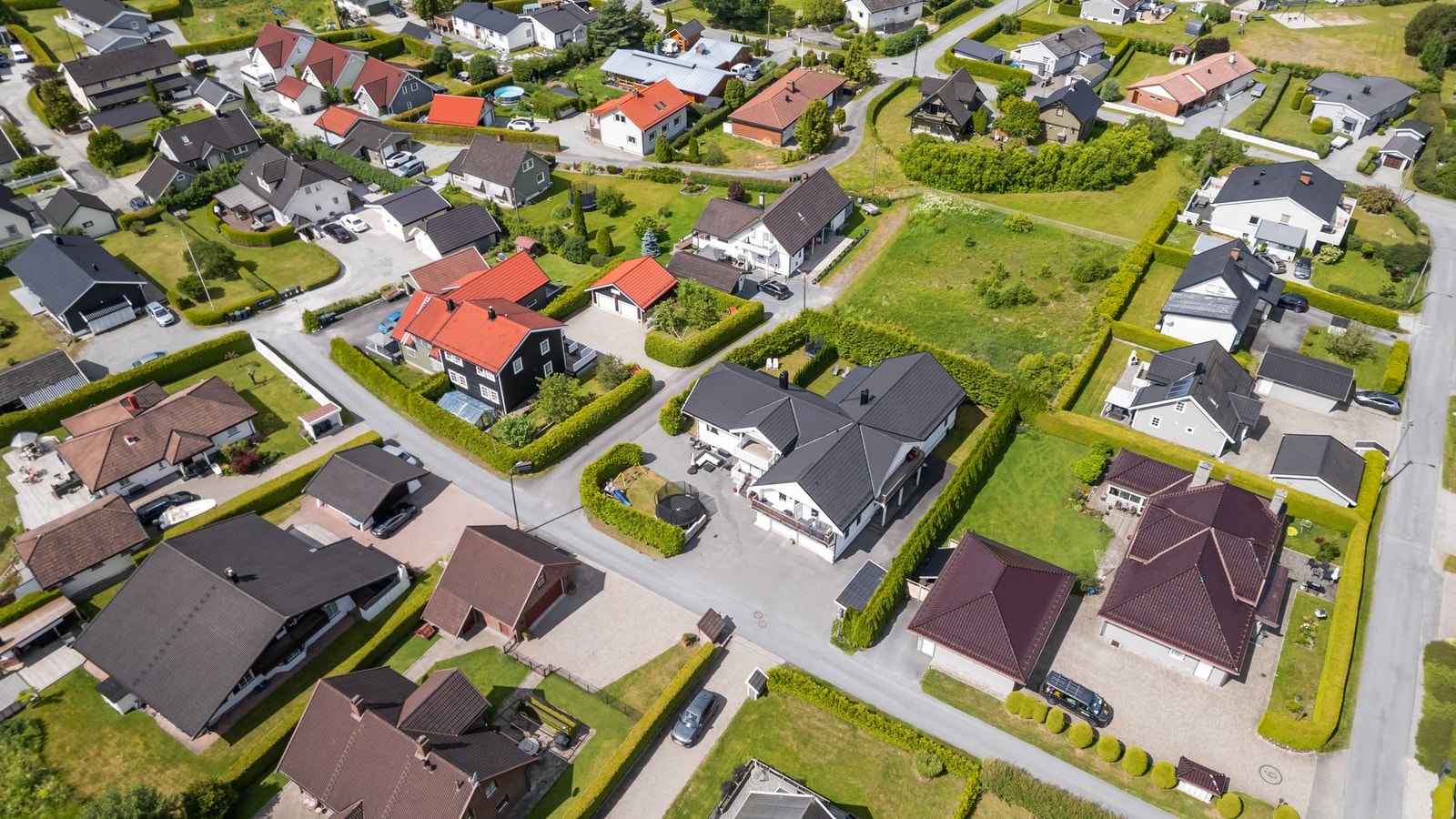 Tomten er pent opparbeidet med asfaltert gårdsplass, plenarealer, hekk og diverse beplantning Galleribilde