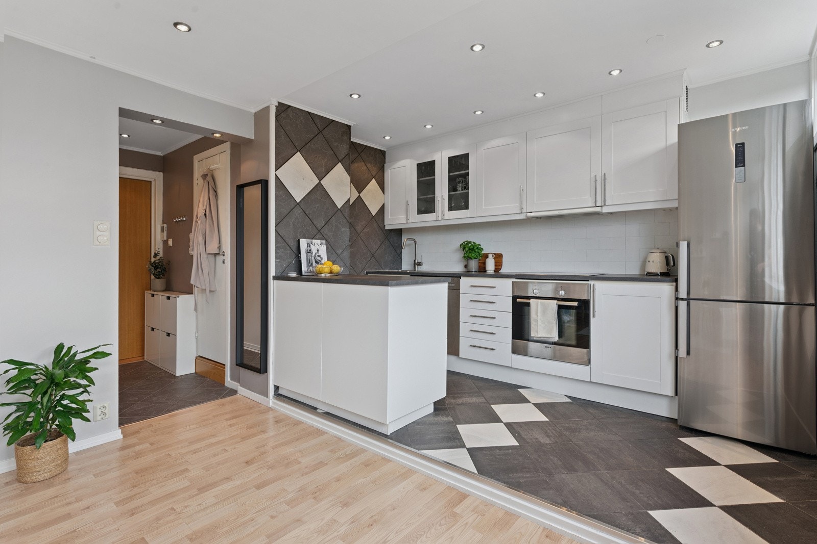 Velholdt kjøkkeninnredning med takhøy innredning, benkeplate i laminat og fliser over benk. Galleribilde