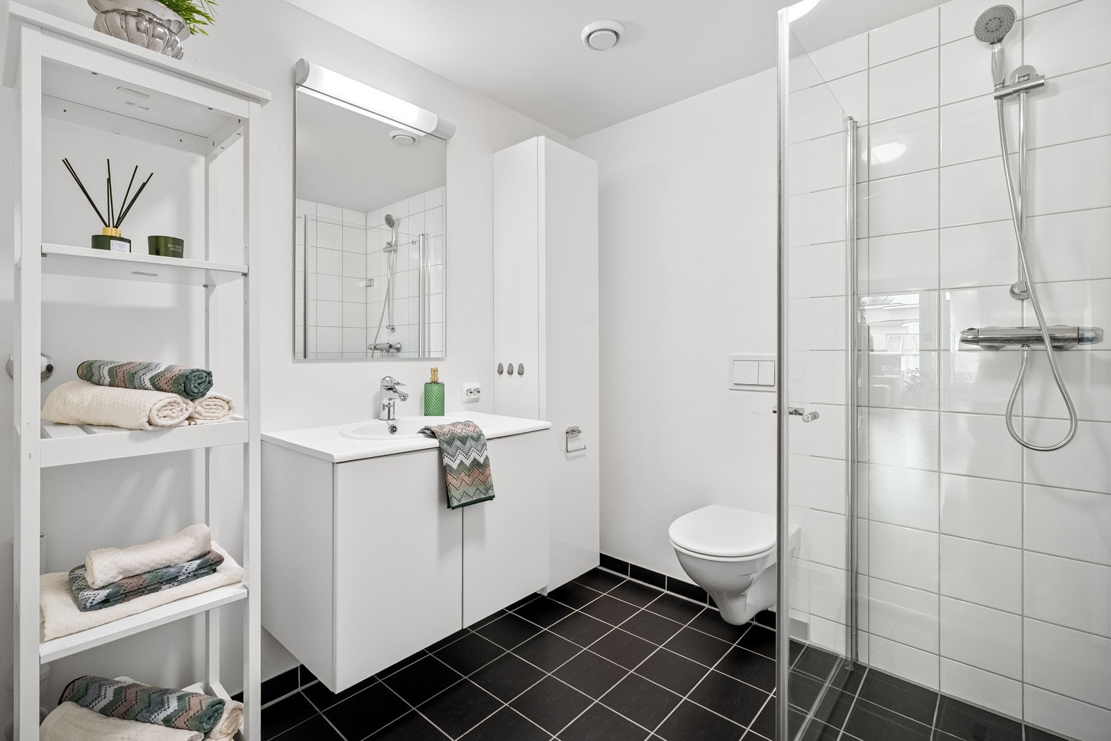 Lekkert helfliset bad med dusjhjørne, vegghengt toalett og inndredning med god lagringsplass. Galleribilde