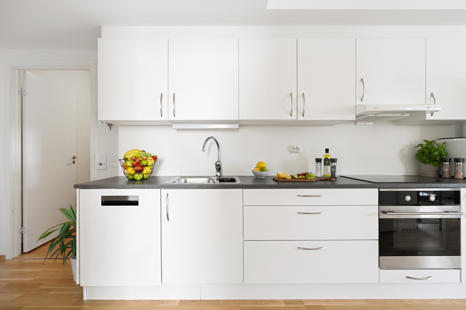 Stilrent kjøkken med lyse fronter og mørk benkeplate. Galleribilde
