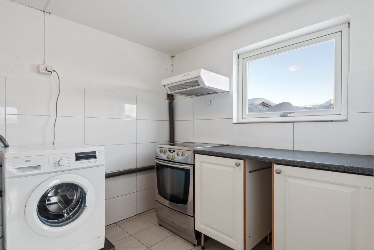 Kombinert kjøkken/vaskerom med flislagt gulvoverflate og dels fliskledde vegger Galleribilde