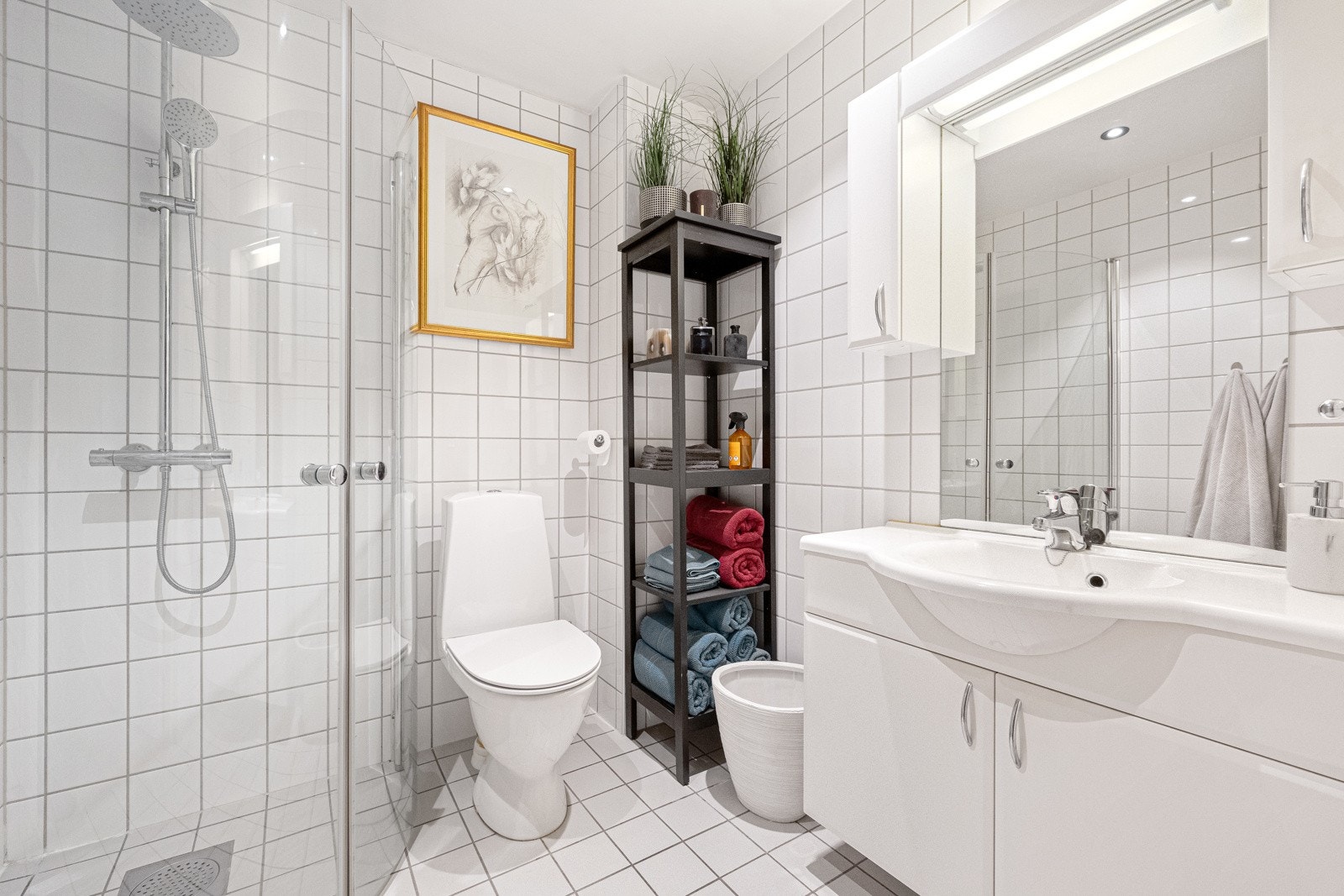 Bad 2 er utstyrt med servant i innredning, overskap med speil og belysning dusj med glassdører og toalett Galleribilde