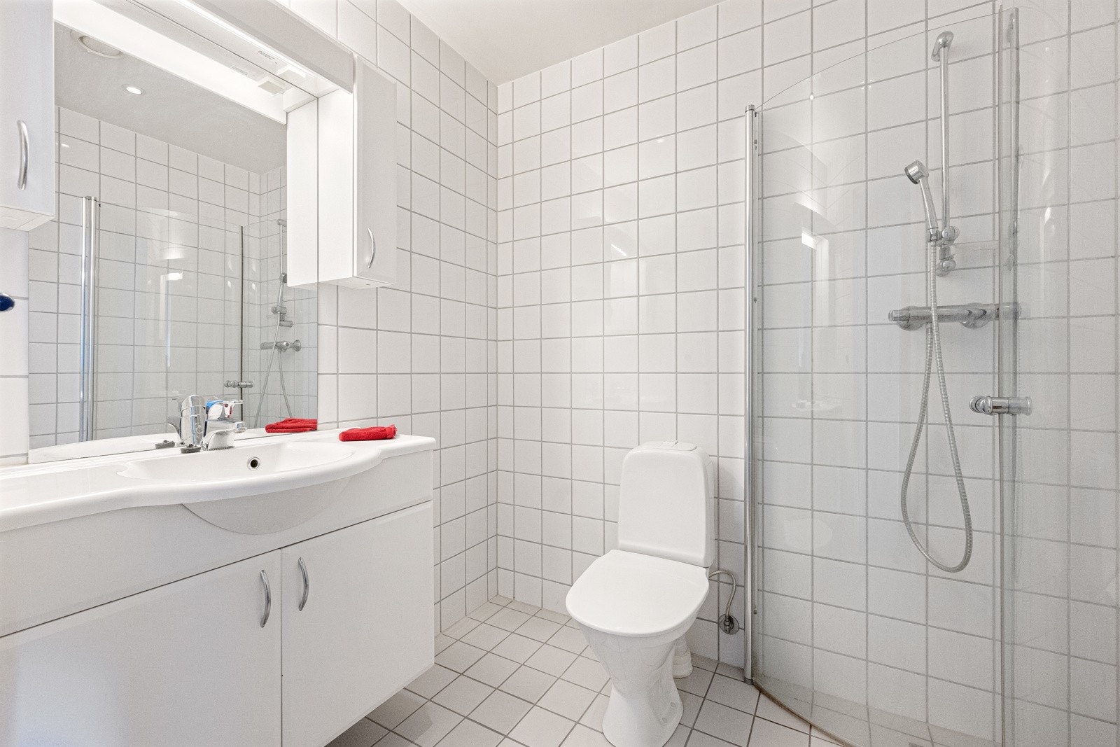 Badet tilhørende hovedsoverommet er utstyrt med servant i innredning, overskap med speil og belysning, dusj med glassdører og toalett Galleribilde