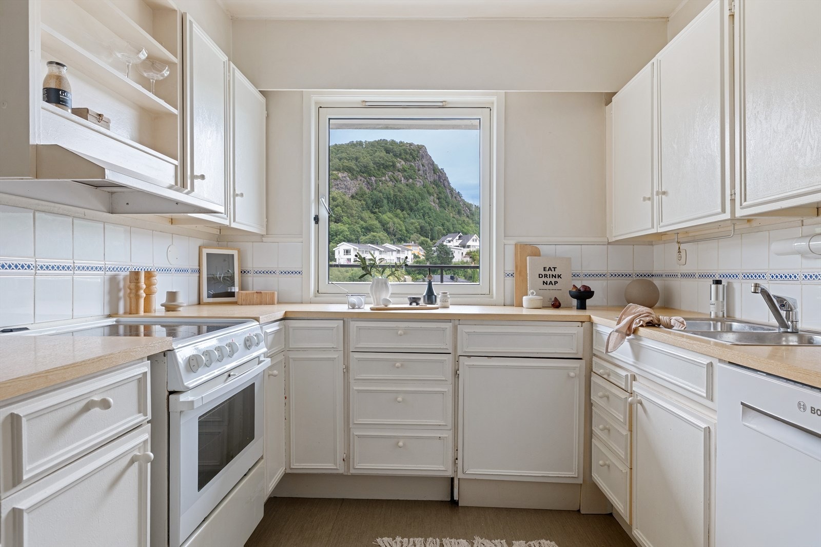 Eldre kjøkken med hvite profilerte fronter og benkeplate av laminat. Galleribilde