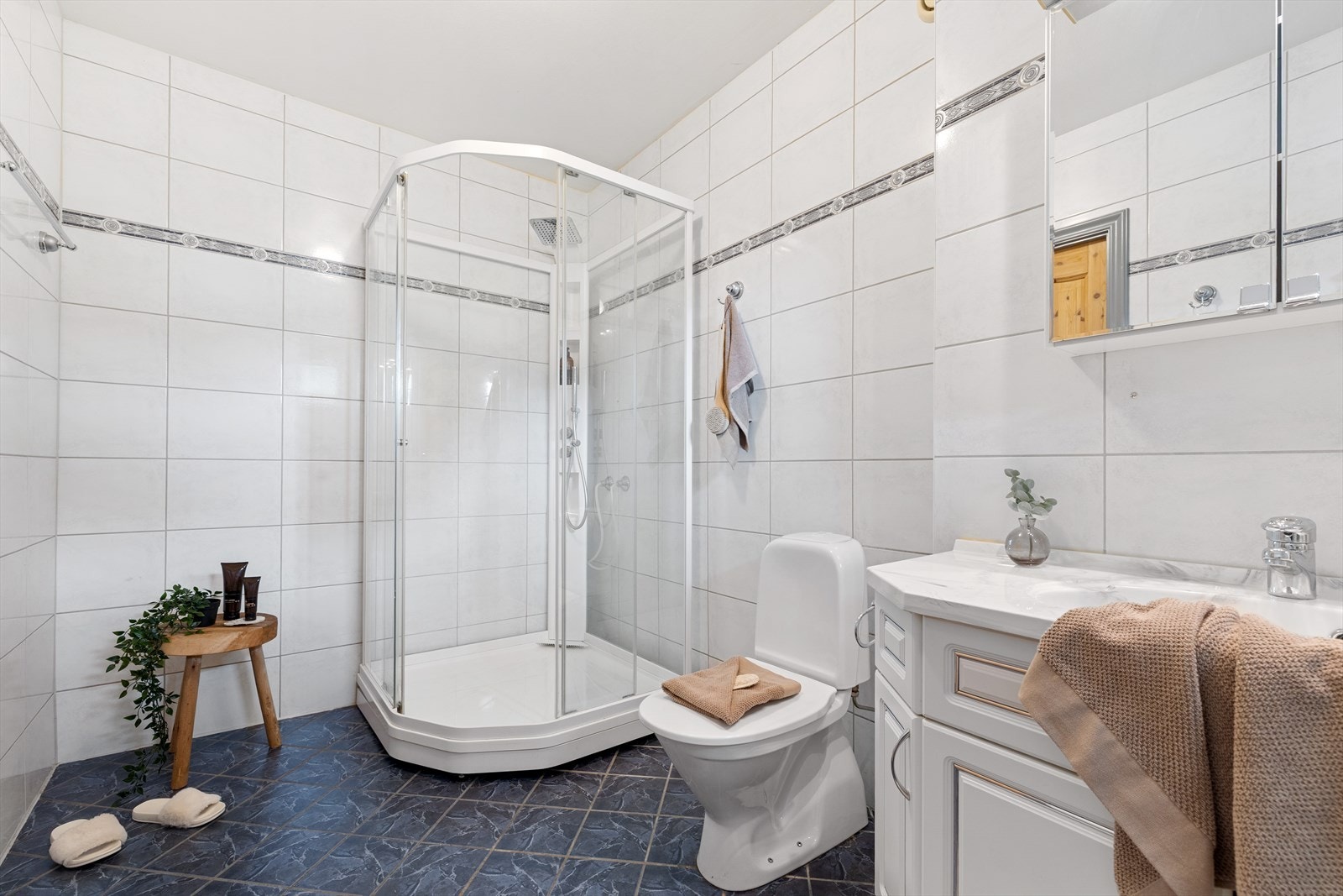 Badet er innredet med toalett, vask med under- og overskap, dusjkabinett, sluk i gulv, avtrekk i vegg, opplegg for vaskemaskin og varmtvannstank. Galleribilde