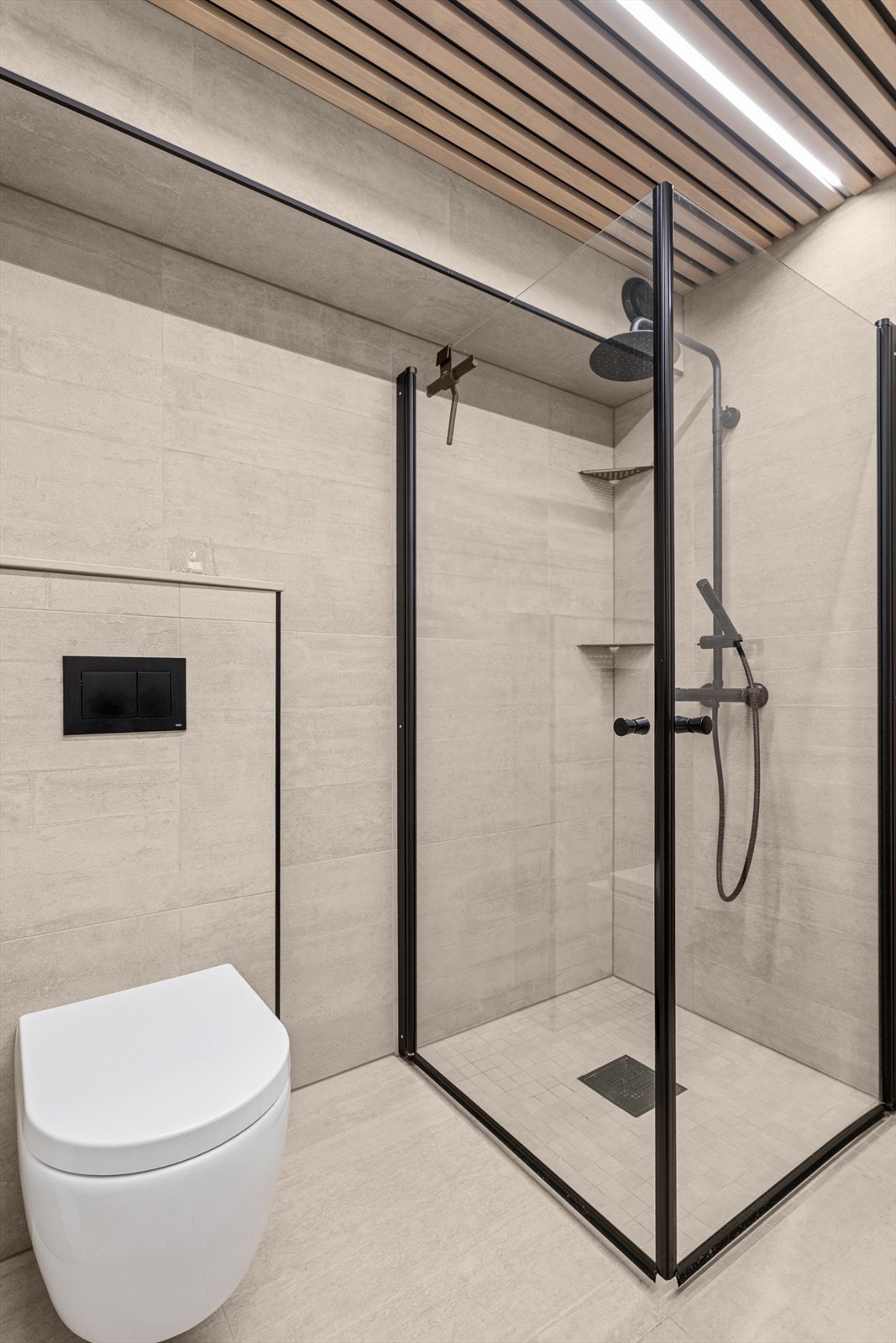 Badet er utstyrt med dusjhjørne, vegghengt toalett, innredning og spilehimling med leddstriper i tak Galleribilde