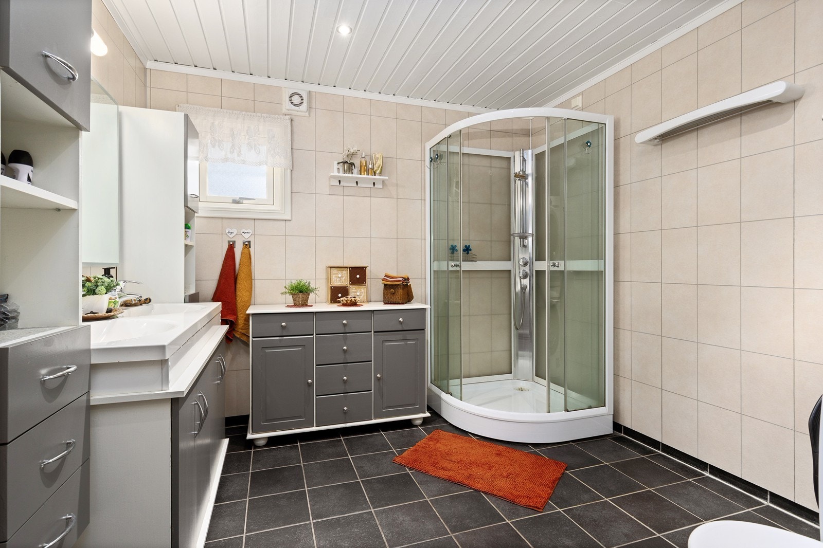 Pent innredet bad med baderomsinnredning med dobbelservant, speil, toalett og dusjkabinett. Galleribilde