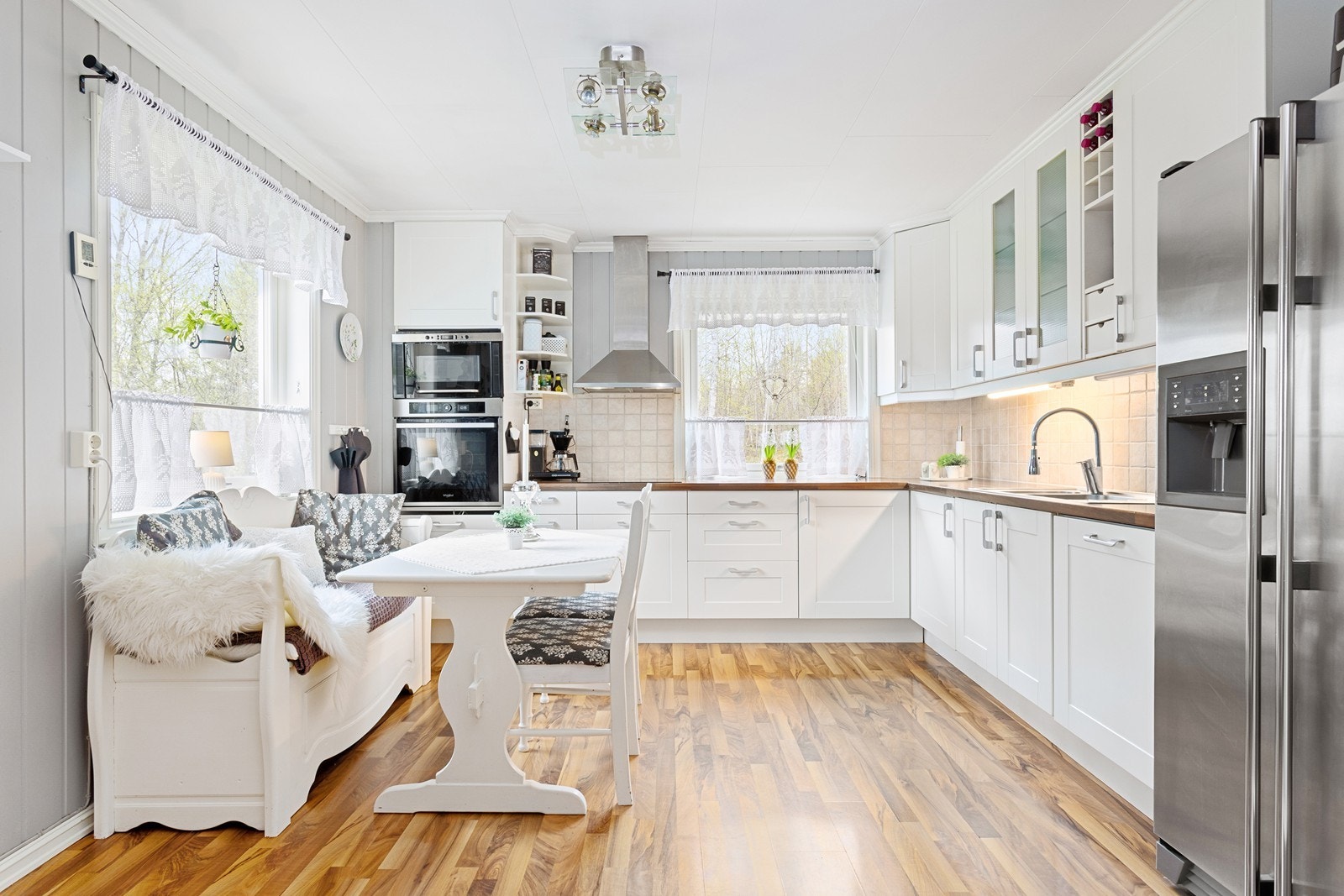 Klassisk kjøkkeninnredning med hvite profilerte fronter og benkeplate av laminat. Galleribilde