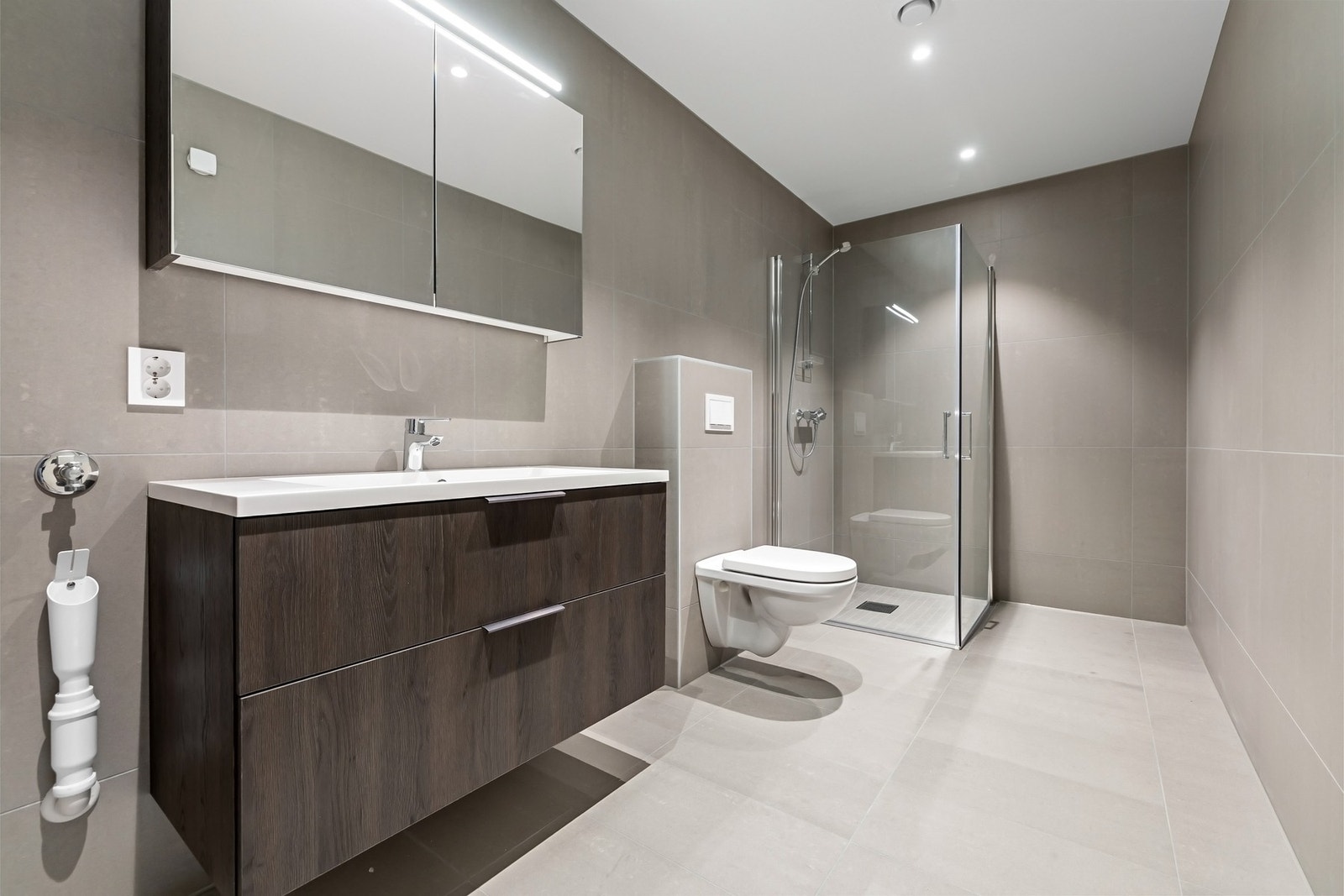 Bad 2: Vegg montert toalett og dusj hjørne - ett bad som kombinerer stil og plass. Her er det også uttak til vaskemaskin. Galleribilde