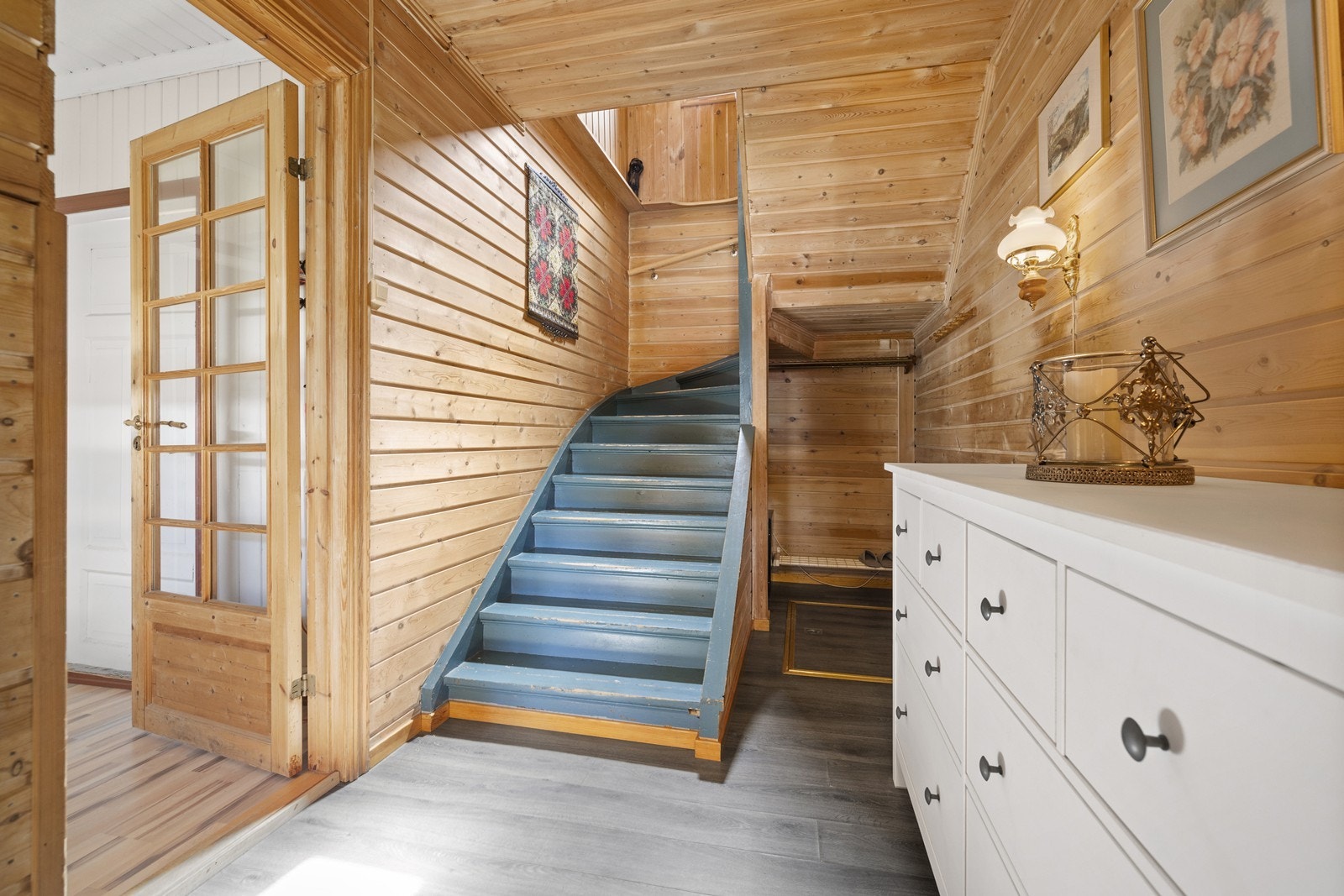 Hall med malt tretrapp som leder opp til andre etasje - gjennomgående bruk av treverk gir lun atmosfære. Galleribilde