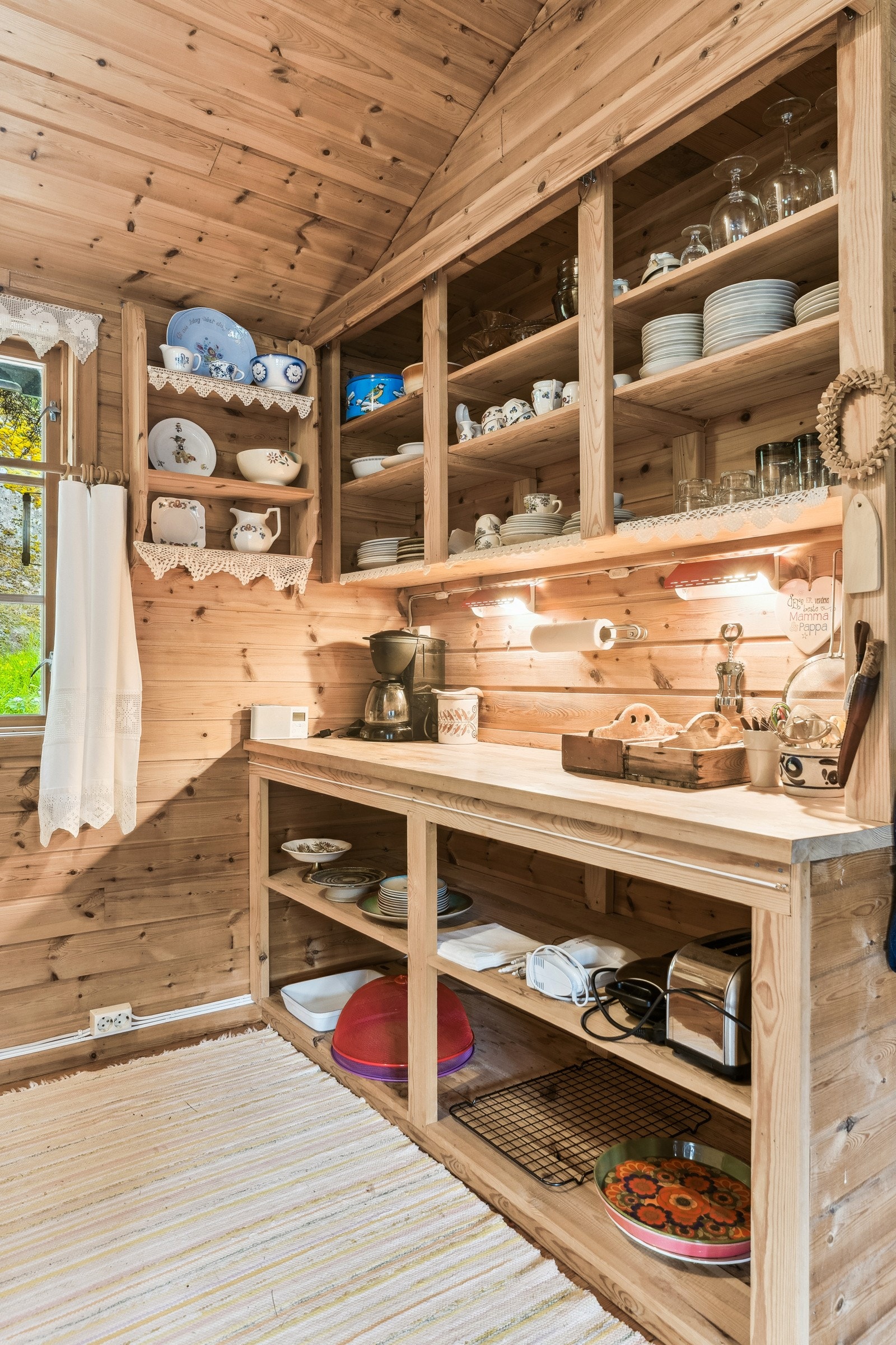 Koselig kjøkken med ei lun og god stemning. Kjøkkenet er praktisk og fint tillaget med trehyller og trebenk og vindauge ut mot inngangsparti Galleribilde