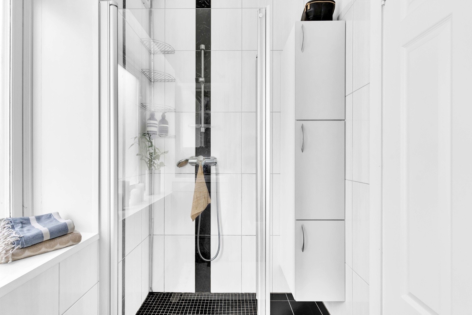 Rommet er innredet med en heldekkende servant plassert på underskap, speil med integrert spotbelysning, vegghengt toalett og dusjhjørne med innadslående dusjdører i herdet glass. Galleribilde