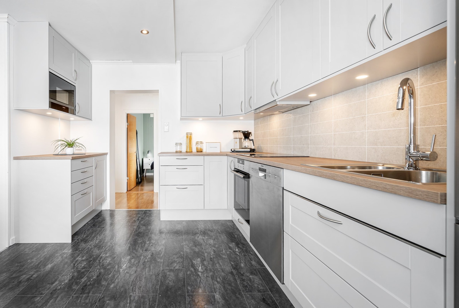 Kjøkkenet har lyse profilerte fronter og benkeplate av laminat med nedfelt oppvaskkum med ett-greps armatur. Galleribilde