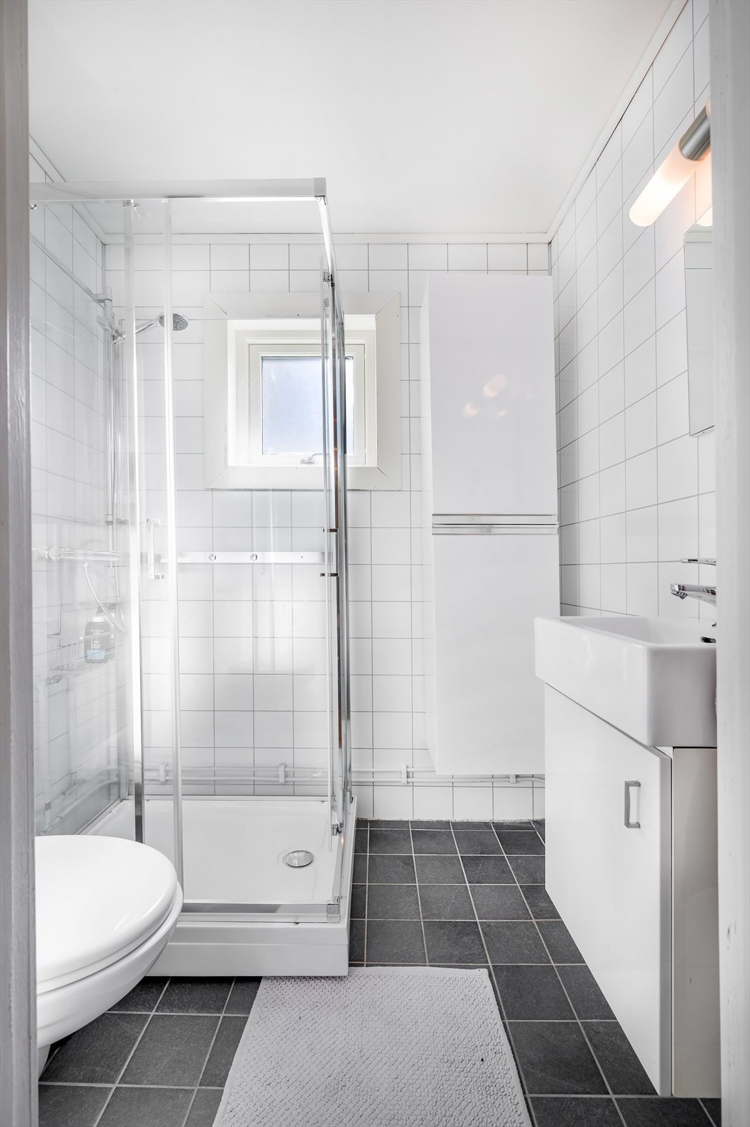 Baderomsinnredning med nedfelt servant, veggmontert toalett og dusjkabinett. Galleribilde