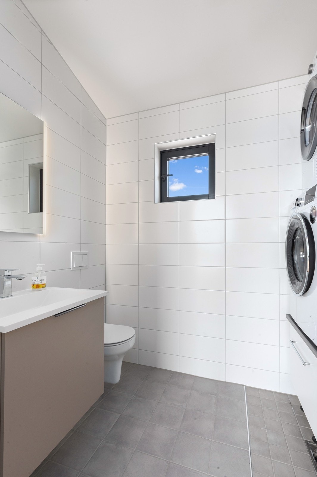 Flislagt gjestetoalett med opplegg til vaskemaskin og tørketrommel. Galleribilde