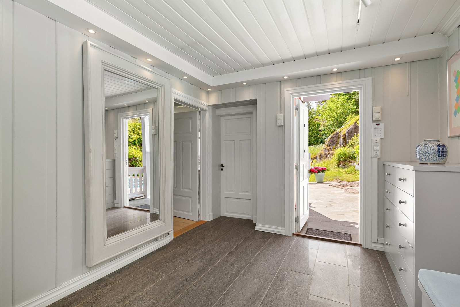 Stor flislagt entré/hall med gulvvarme, garderobe og møbler fra Vegårshei Trevare. Galleribilde