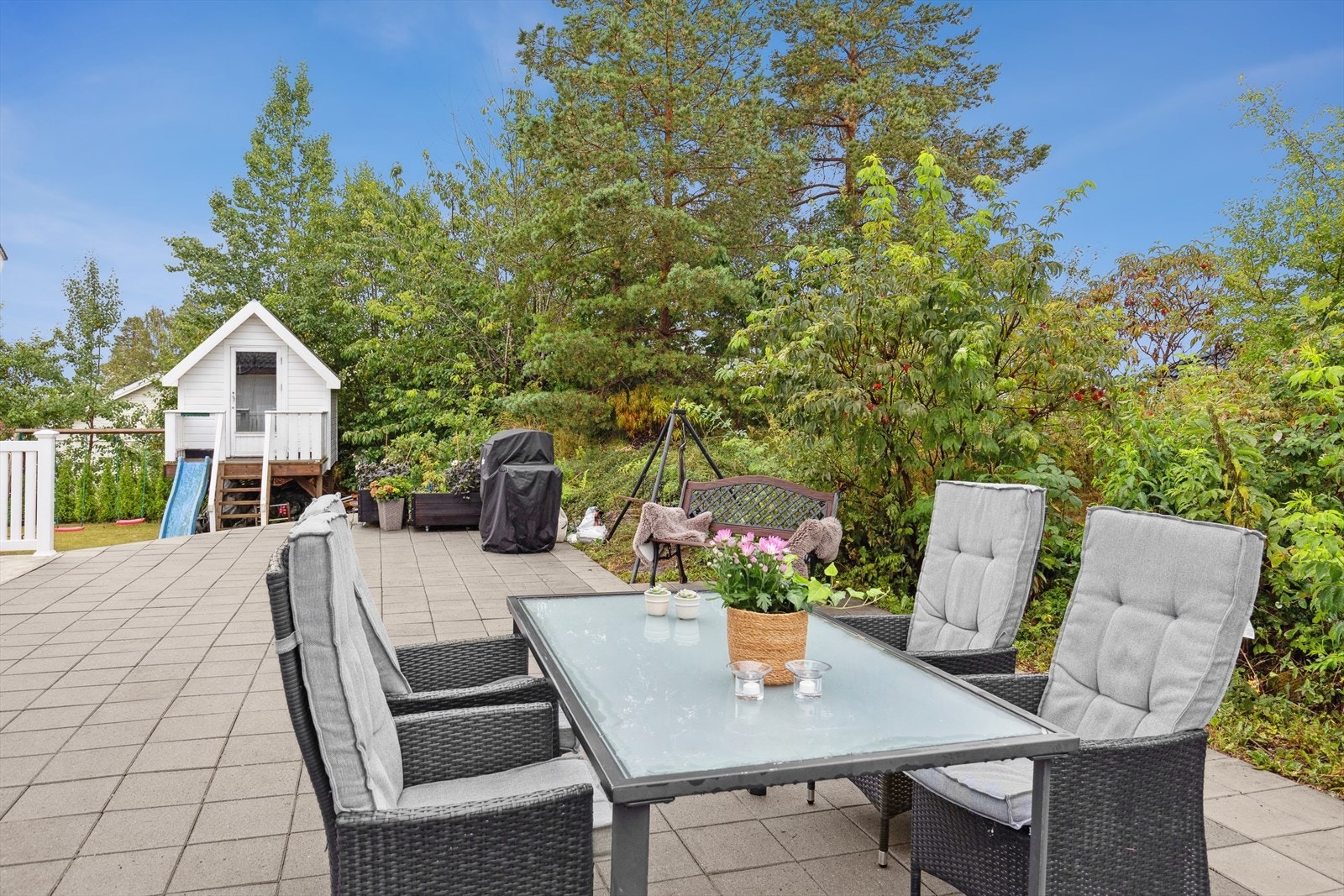 Steinbelagt uteplass med plass for utemøbler, grill og bålpanne. Det er direkte utgang til hagen. Galleribilde