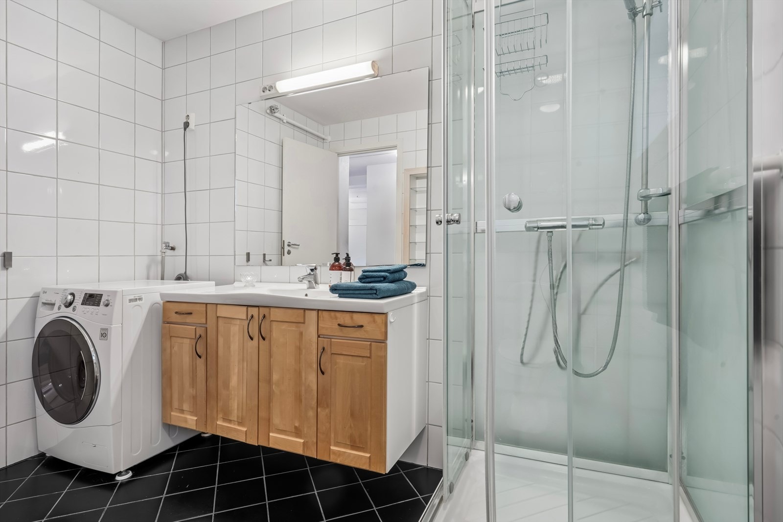 Baderommet er flislagt med varmekabler og har montert dusjkabinett og opplegg for vaskemaskin Galleribilde