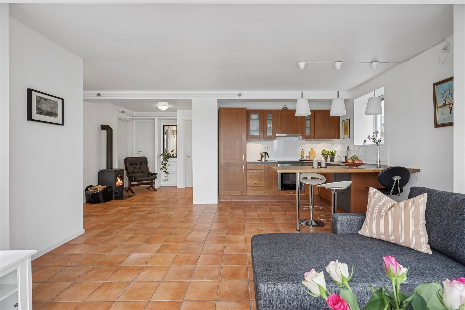 Her er det flislagt gulv og åpen løsning mellom stue og kjøkken. Også i denne etasjen er det tilkoblet vedfyring Galleribilde