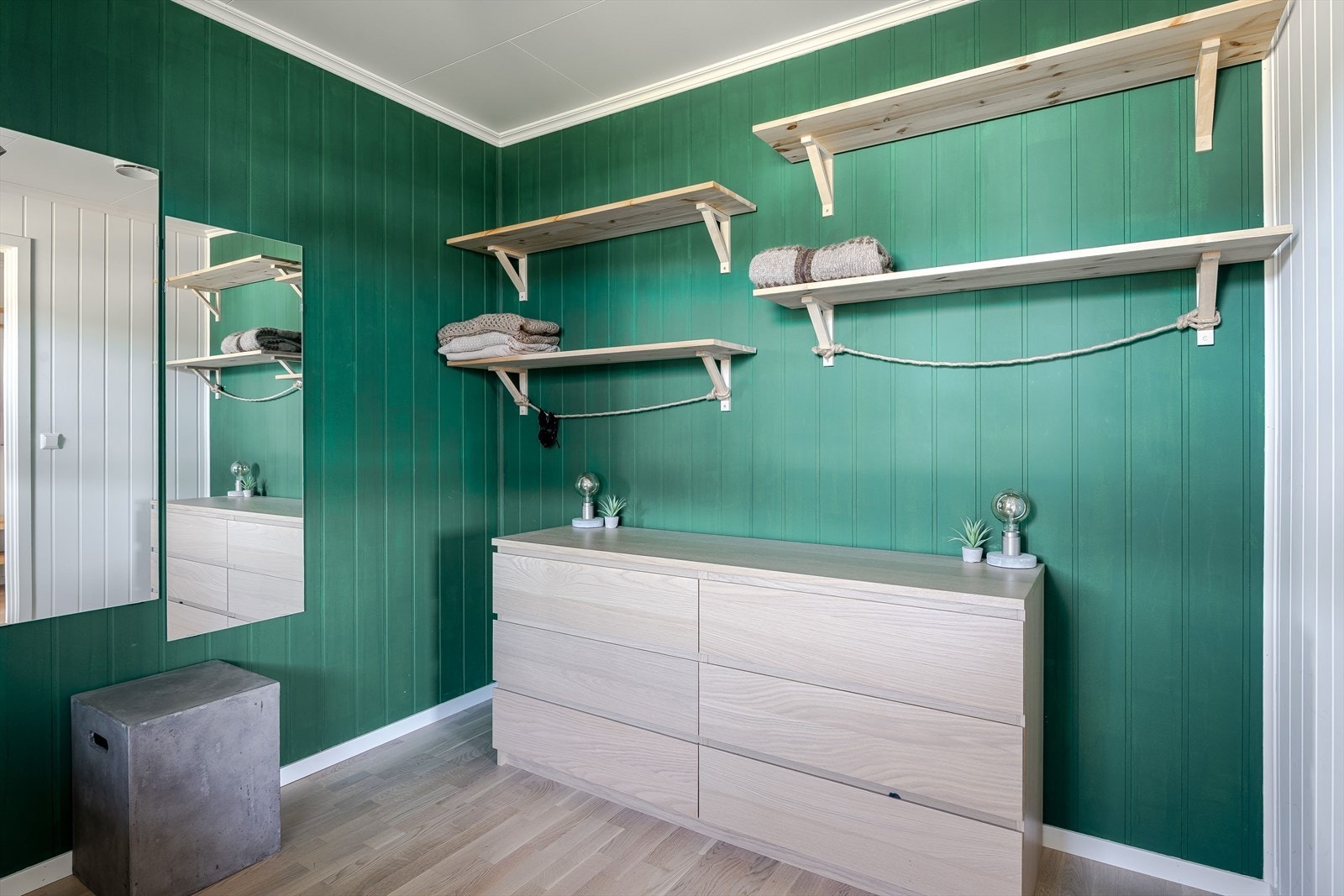 Rommet har to vegger malt i en nydelig grønnfarge. Fine detaljer med vegghengte hyller og flott løsning for oppheng. Galleribilde