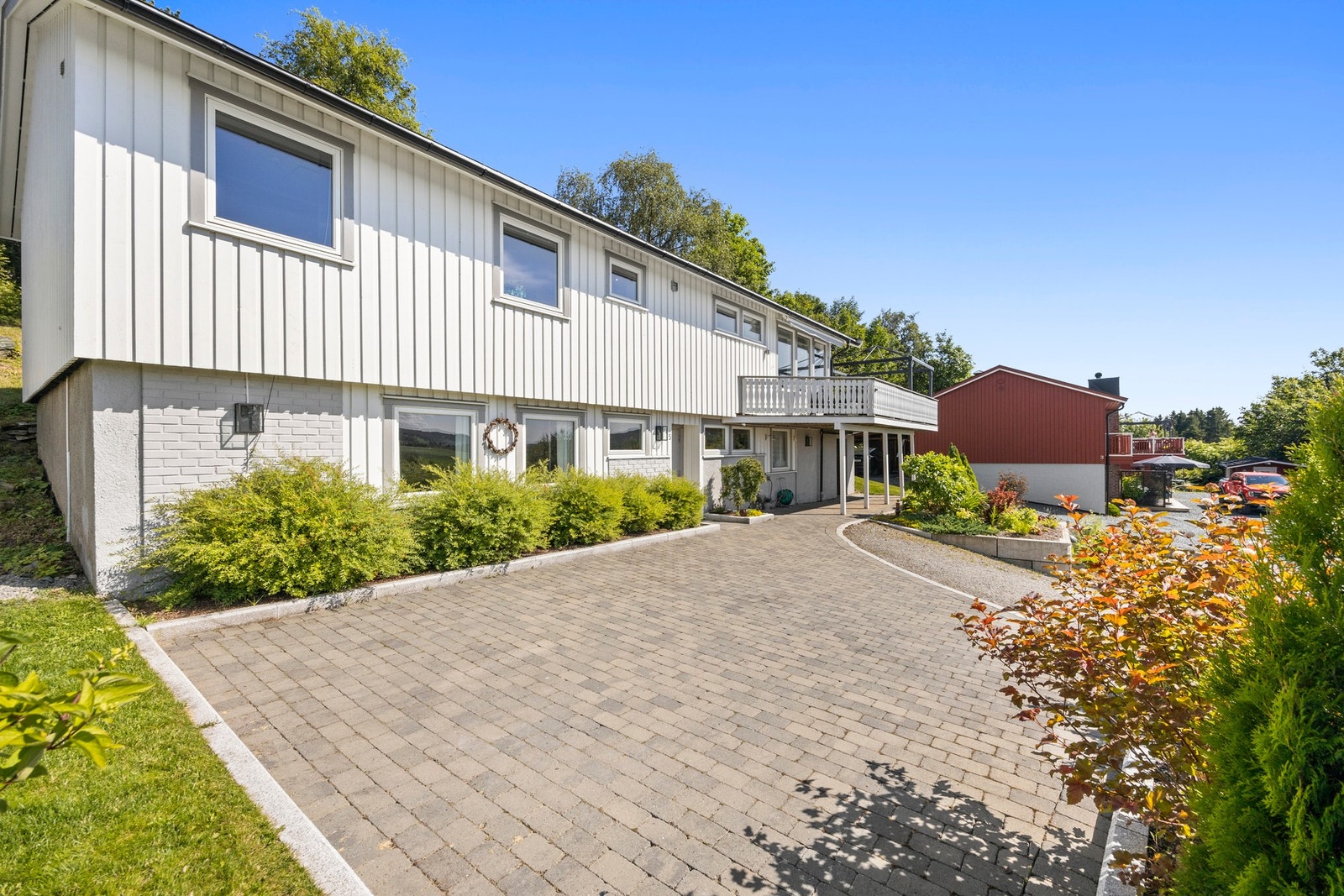 Inngangspartiet er steinlagt som sammen med steinkant mot plen og blomsterbed gir et svært godt førsteinntrykk av eiendommen! Galleribilde