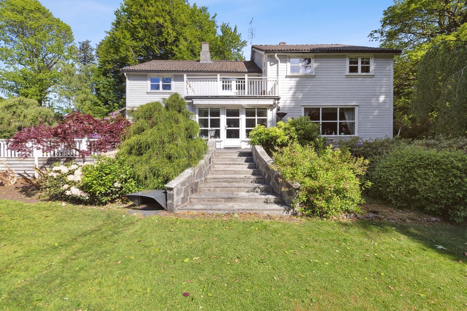 Boligens terrasse ligger skjermet til, med flott utsyn mot den frodige hagen og grønne omgivelser, noe som skaper en fredelig og avslappende atmosfære. Perfekt for lange sommerdager og sosiale sammenkomster. Galleribilde